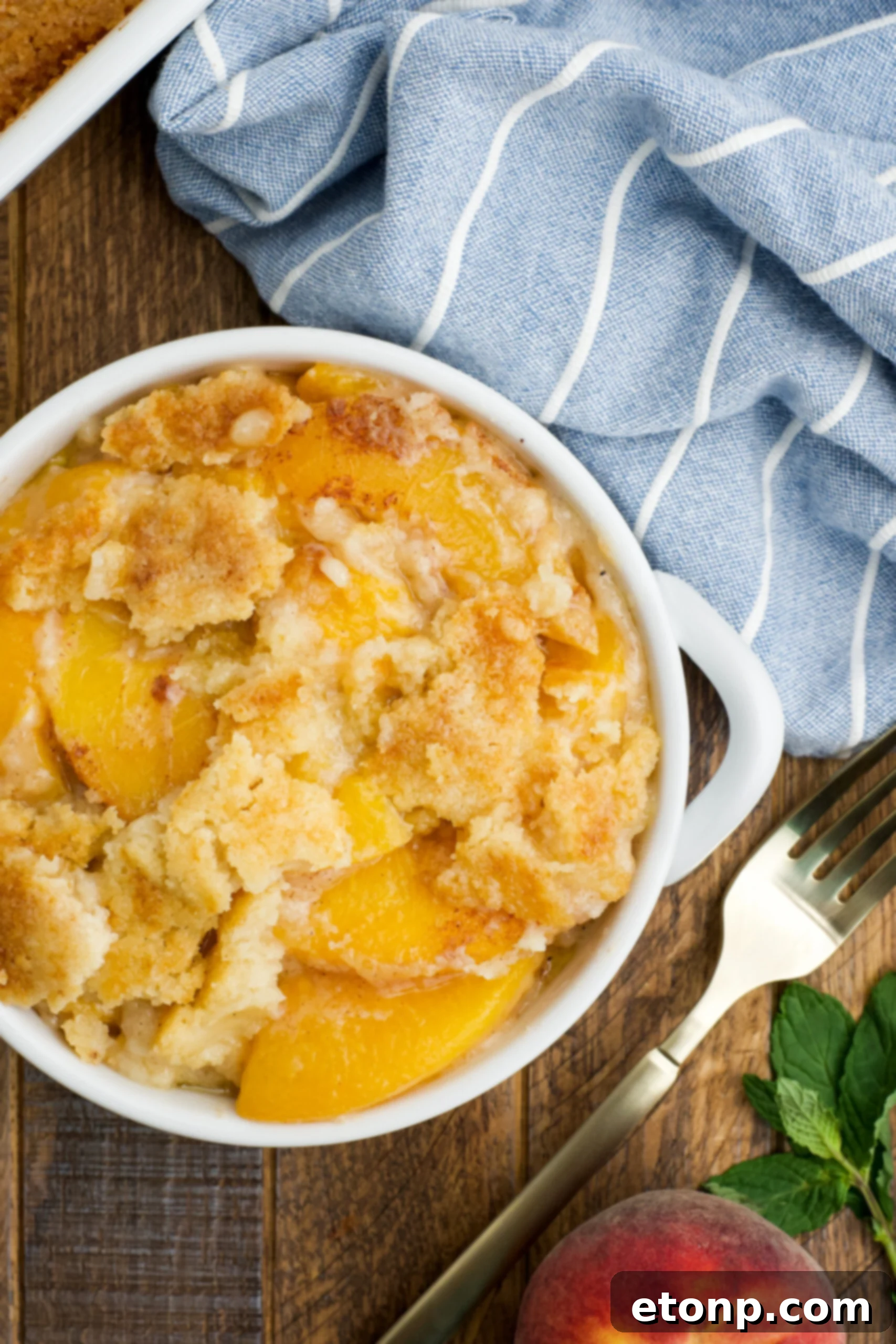 Overhead view of a serving of Peach Dump Cake in a white bowl.
