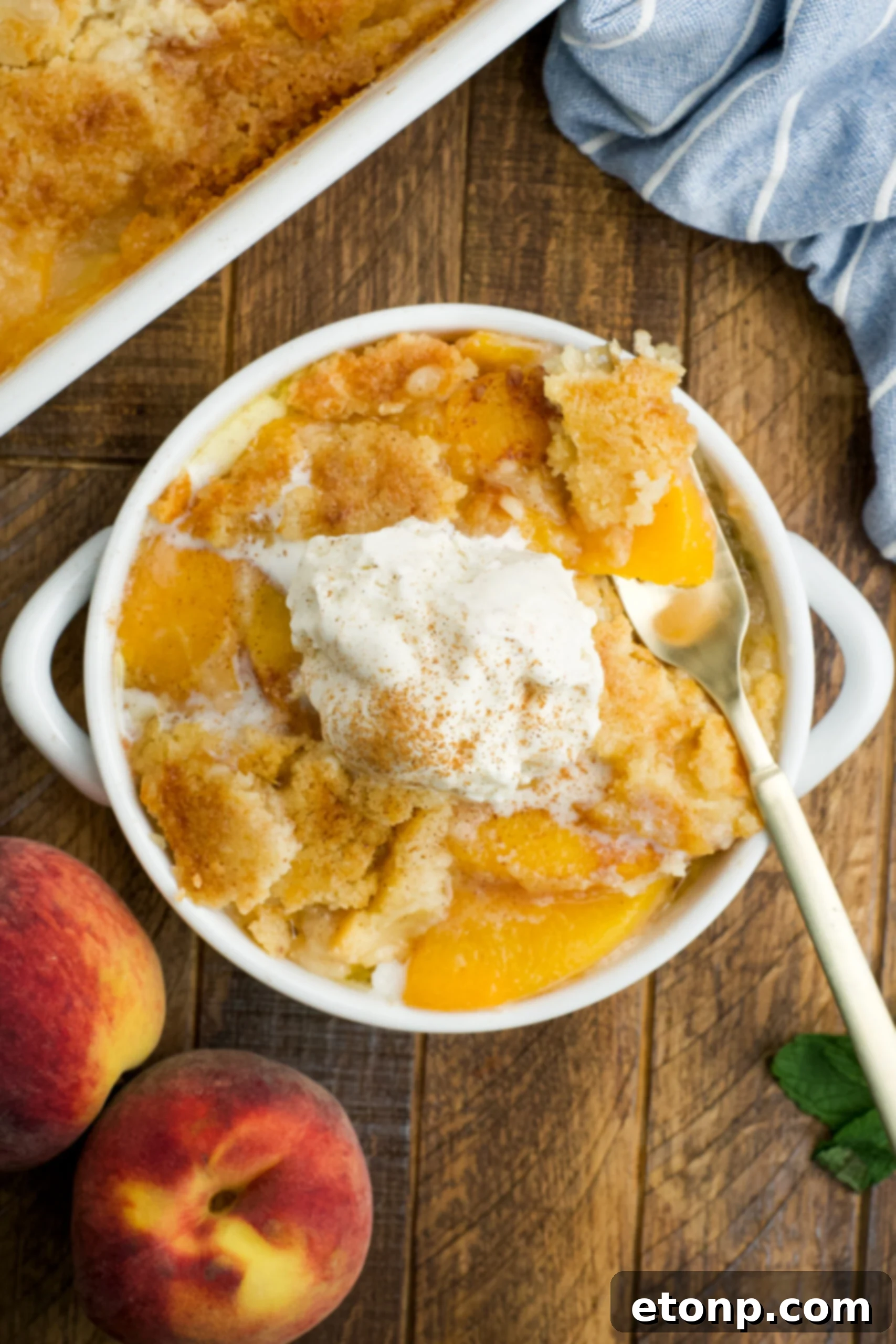 Overhead view of a serving of Peach Dump Cake in a white bowl topped with a scoop of vanilla ice cream.