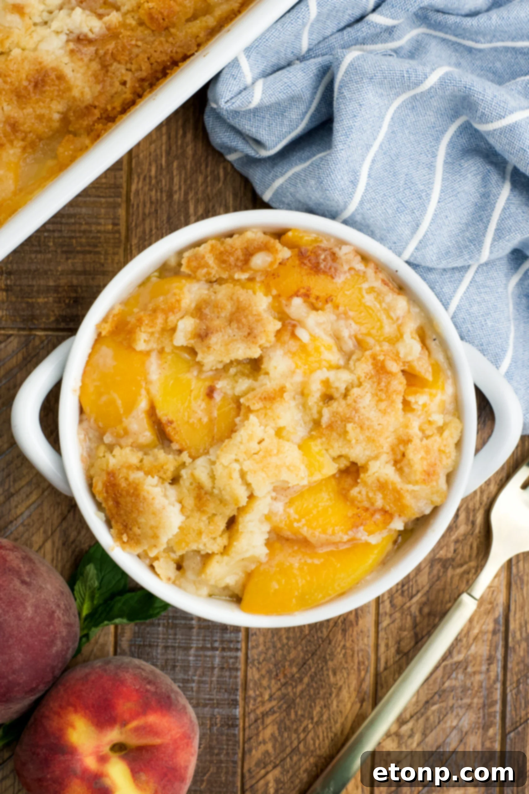 Overhead view of a serving of Peach Dump Cake in a white bowl.