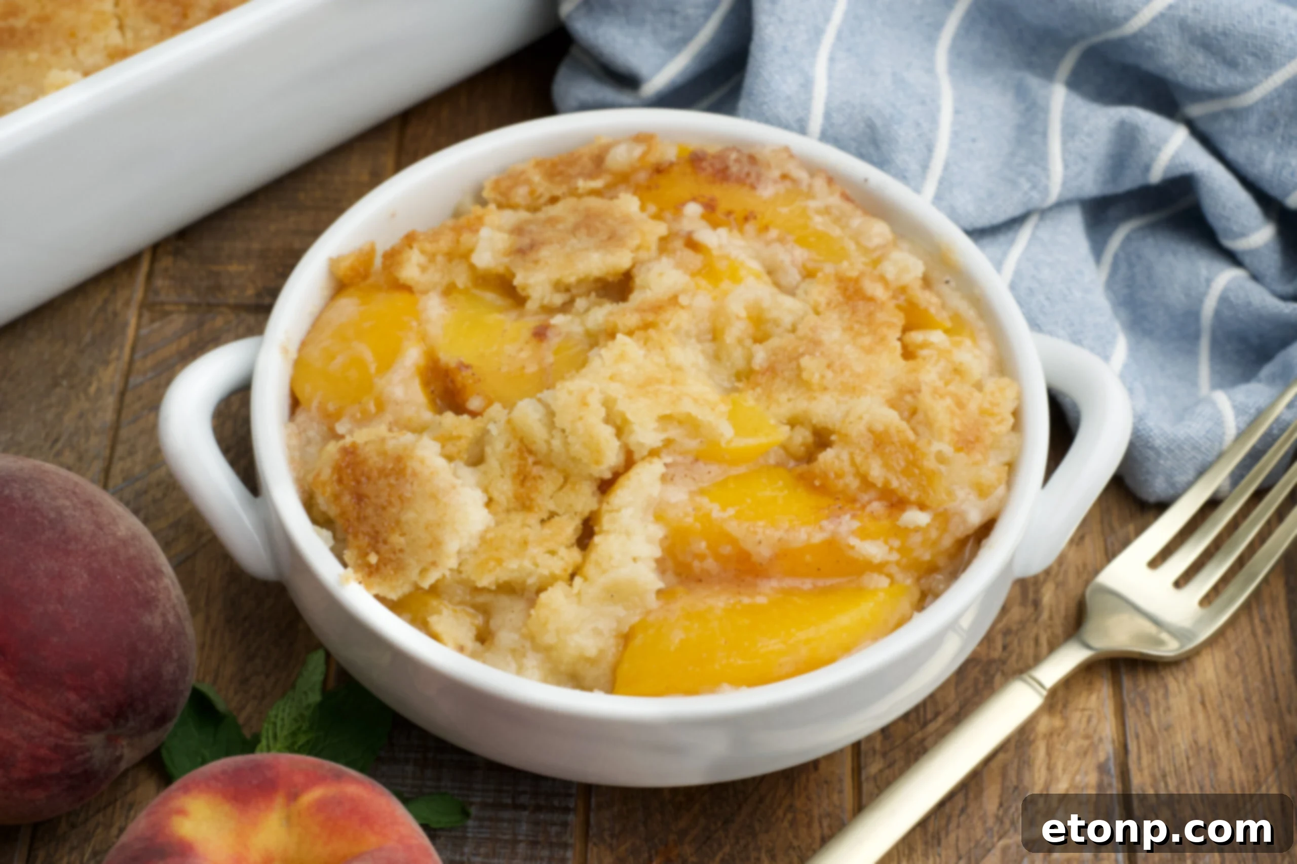 Overhead view of a serving of Peach Dump Cake in a white bowl.