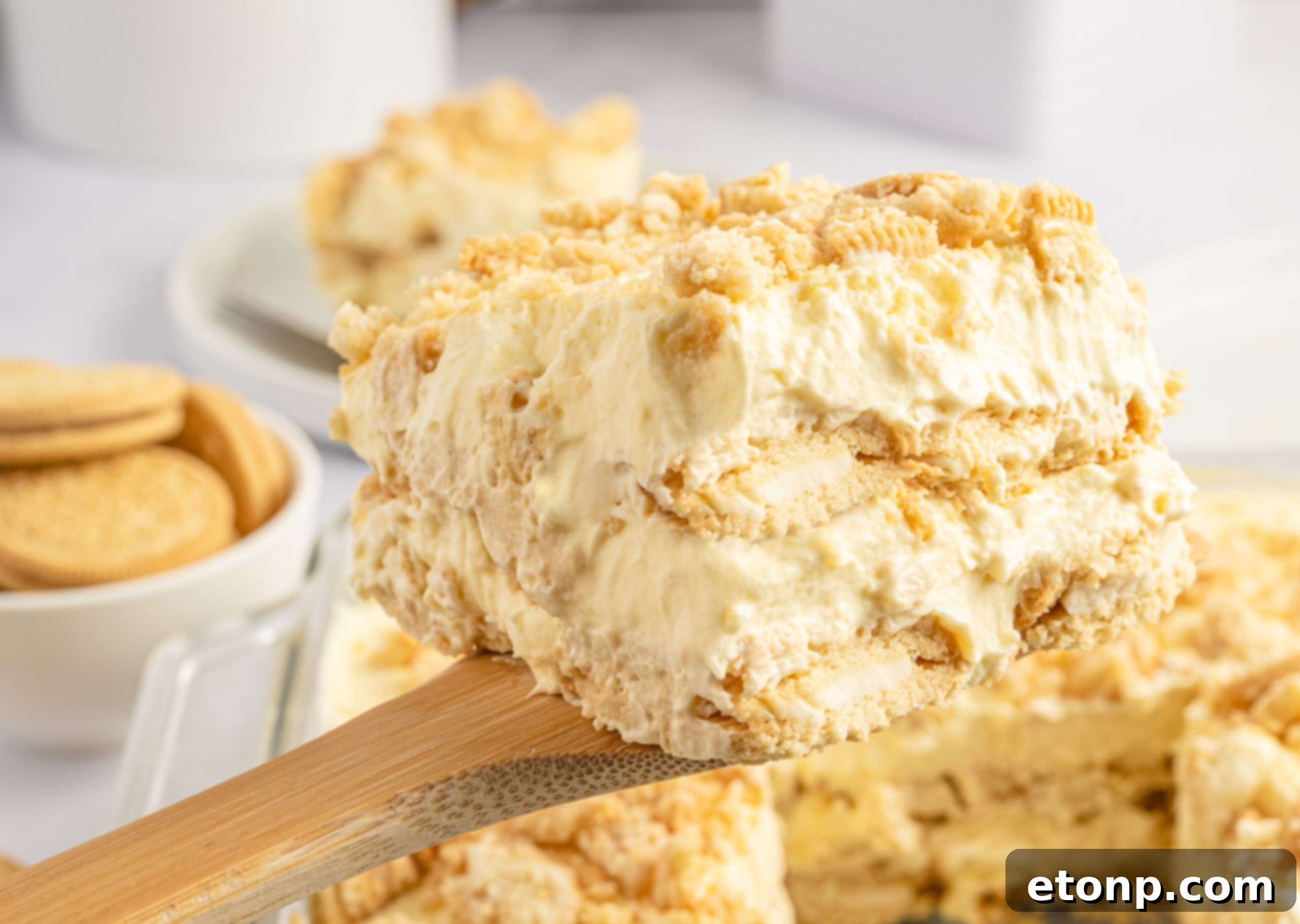 Close up view of a slice of Golden Oreo Icebox Cake being lifted up on a wooden spoon, showing its integrity.