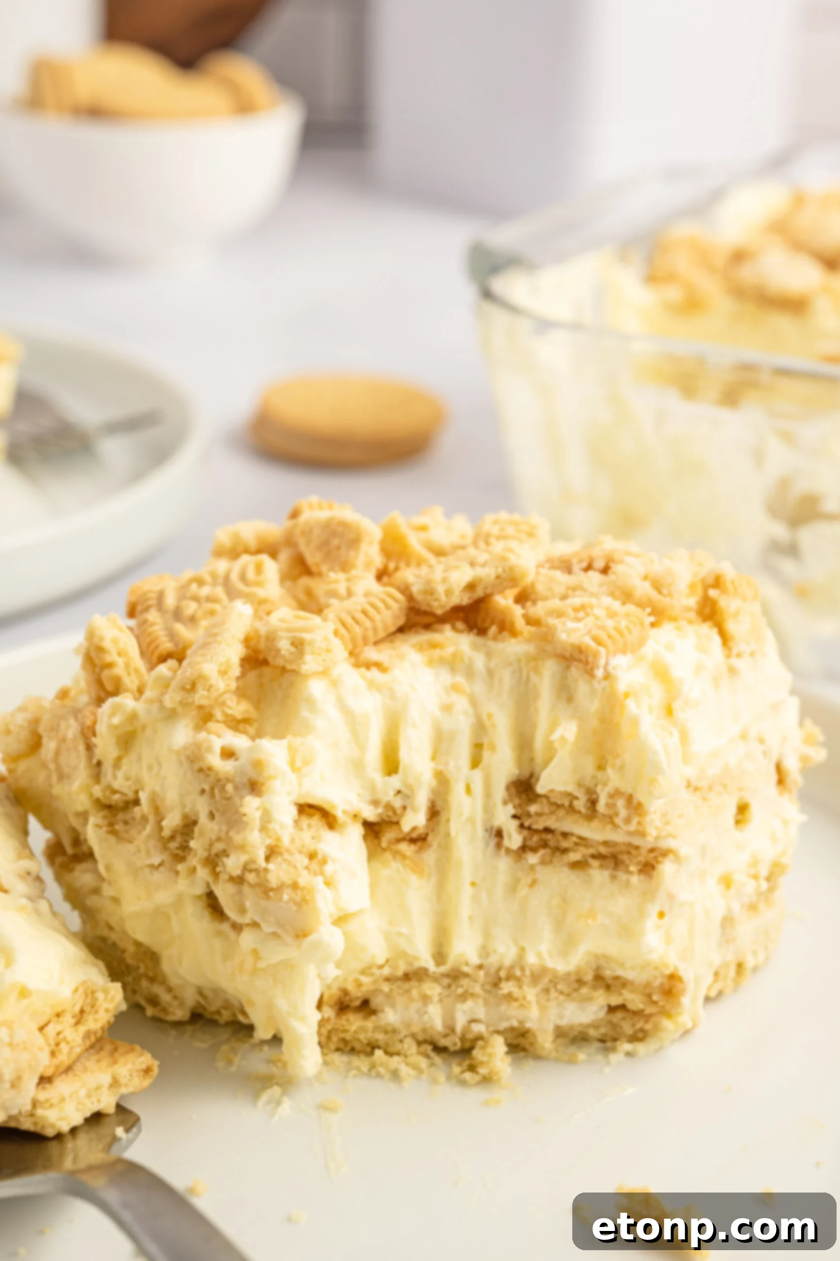 Front view of a slice of Golden Oreo Icebox Cake with a bite removed by a silver fork, showing the texture.