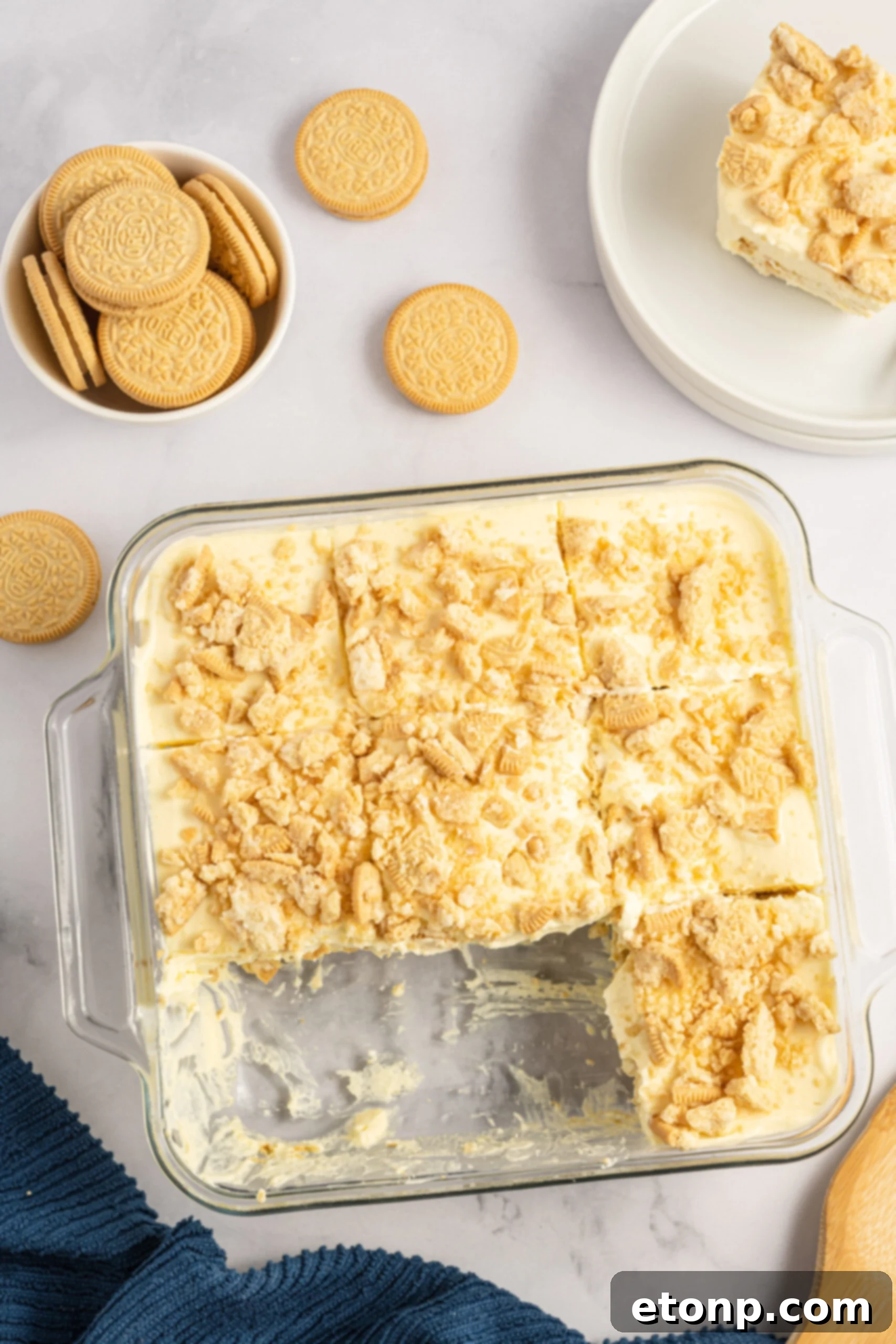 Overhead view of Golden Oreo Icebox Cake in a clear baking dish with two slices neatly removed, revealing the inner layers.