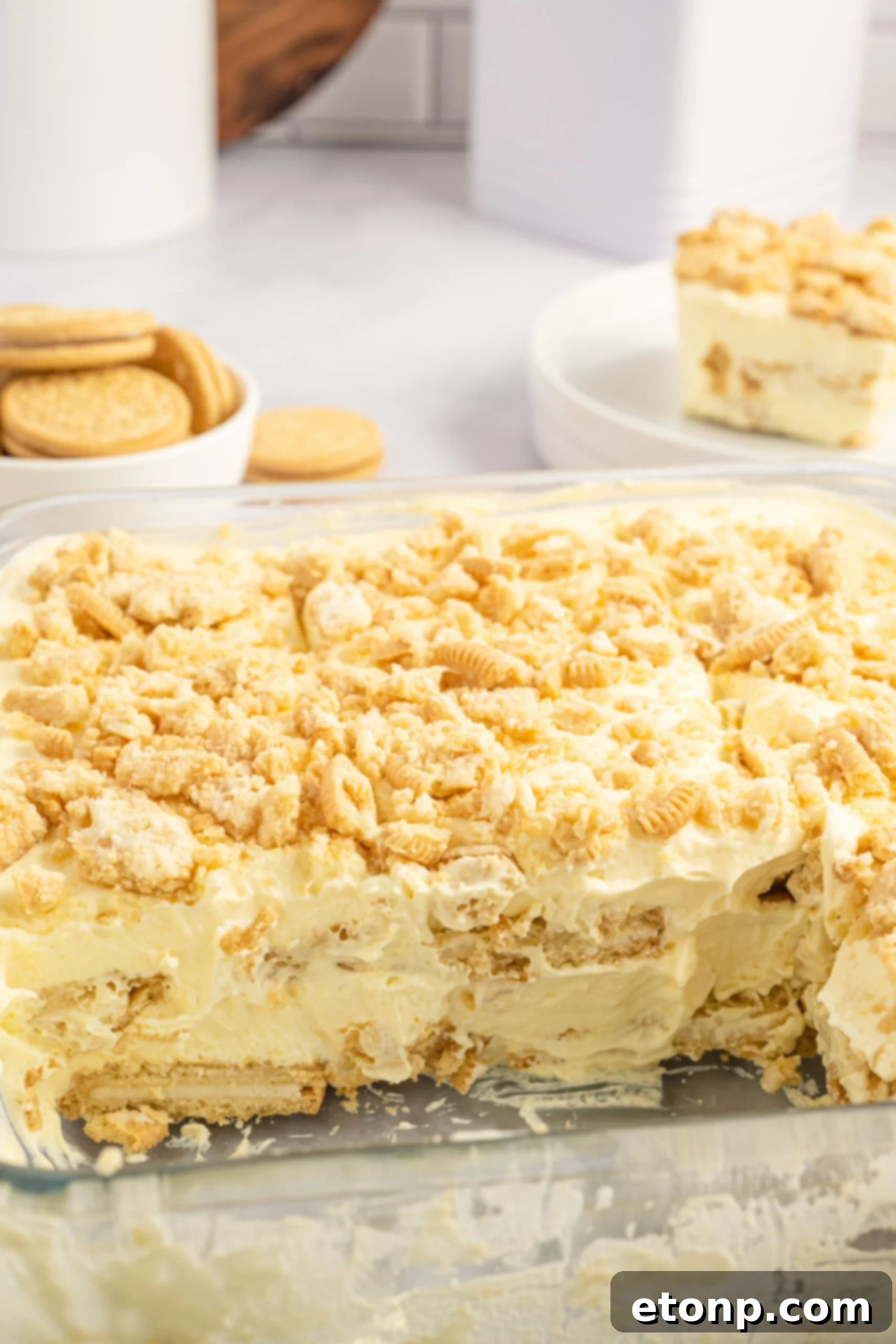 Close up view of Golden Oreo Icebox Cake in a clear baking dish with two slices removed, showing detail of the creamy layers.