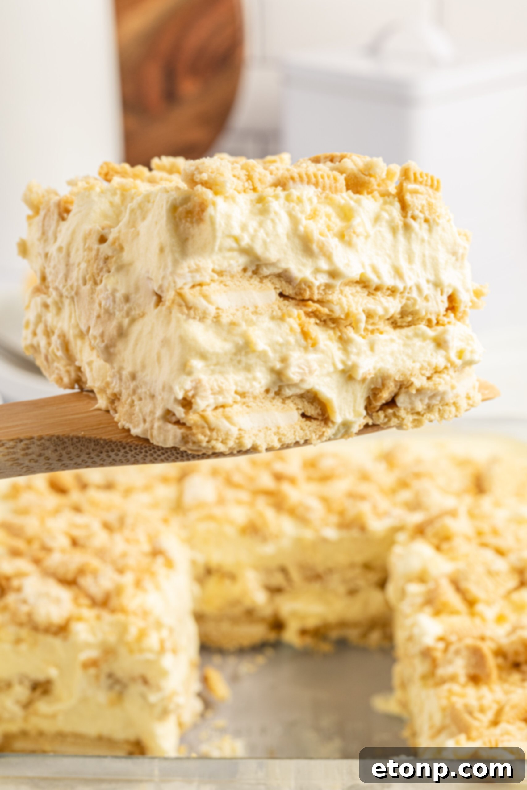 Front view of a slice of Golden Oreo Icebox Cake on a wooden spatula, ready to be transferred to a plate.
