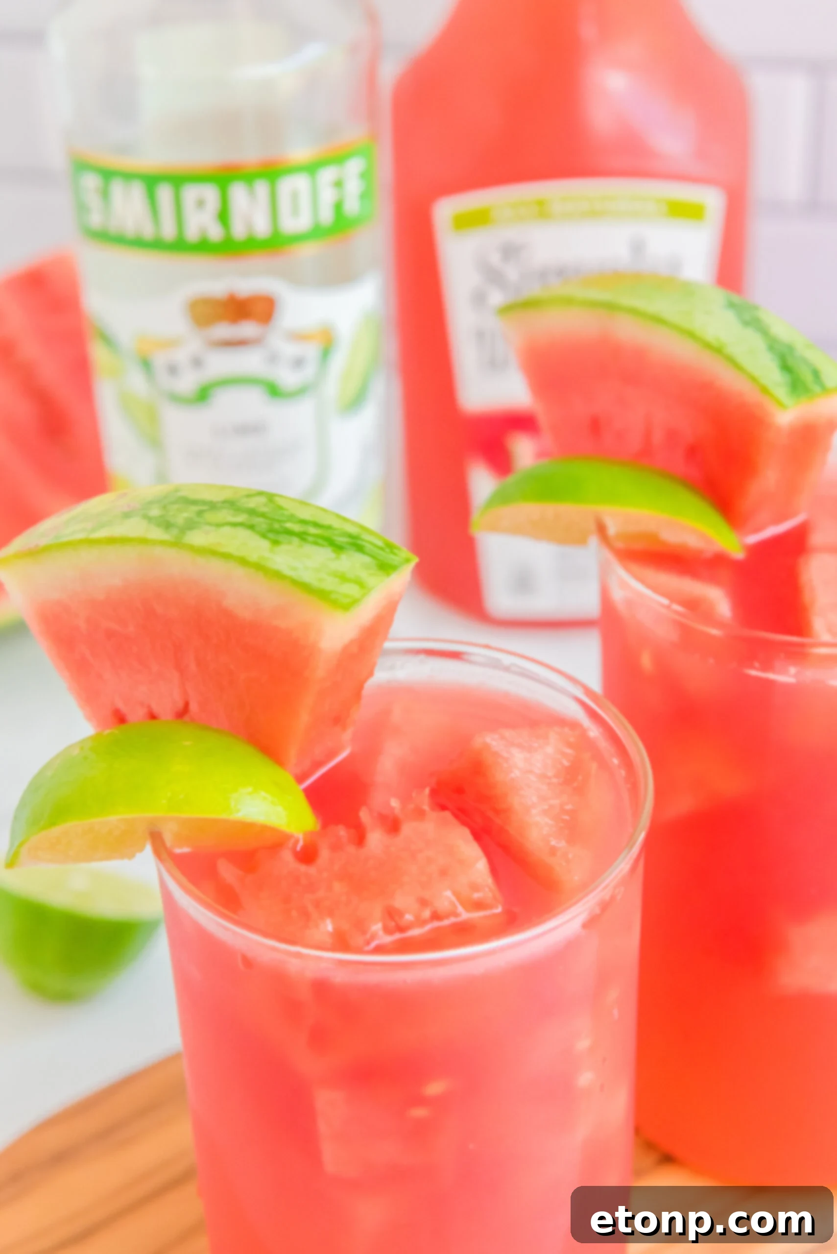 Close up view of Watermelon Cocktail in two clear glasses garnished with lime and watermelon slices.