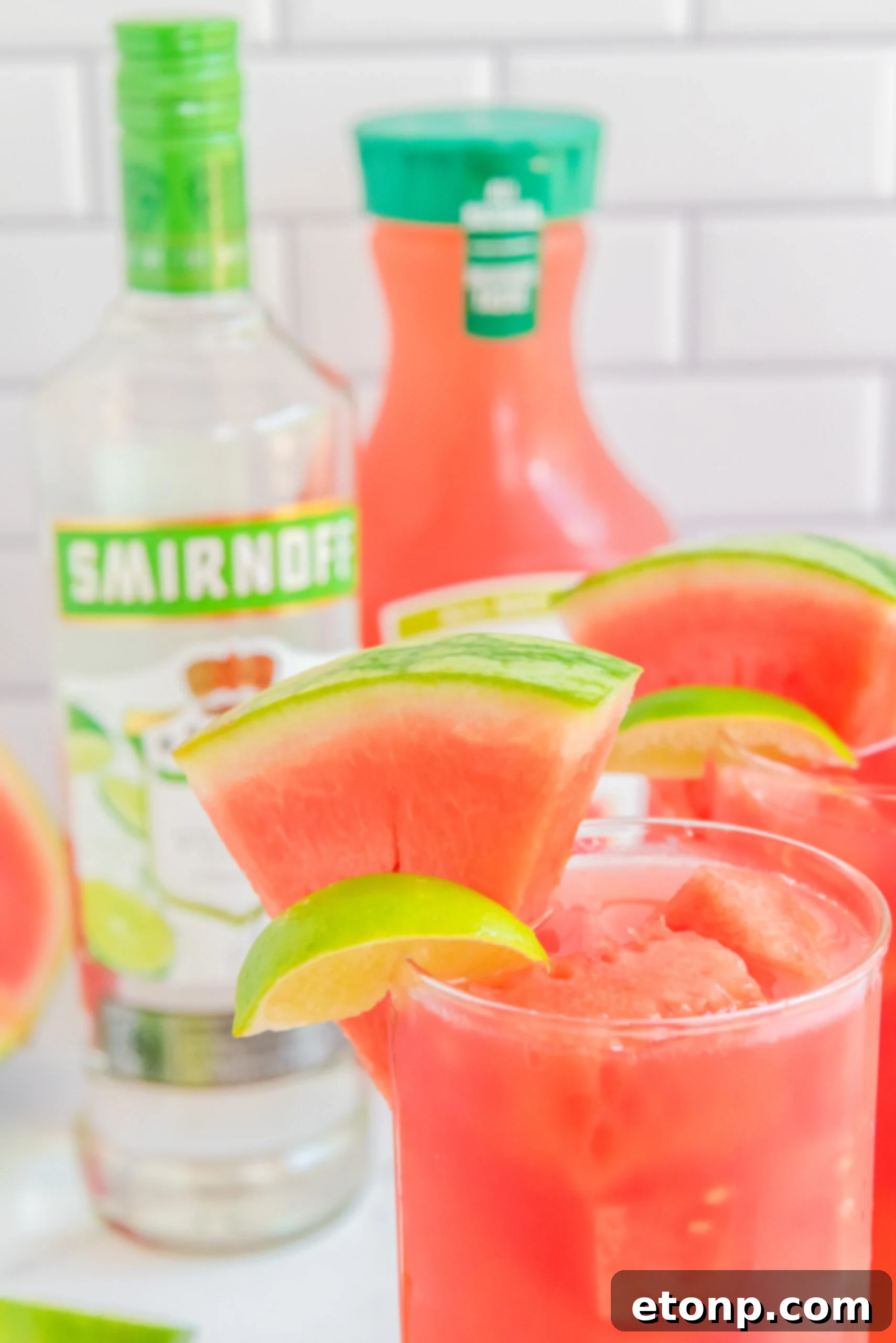 Close up view of Watermelon Cocktail in two clear glasses garnished with lime and watermelon slices.