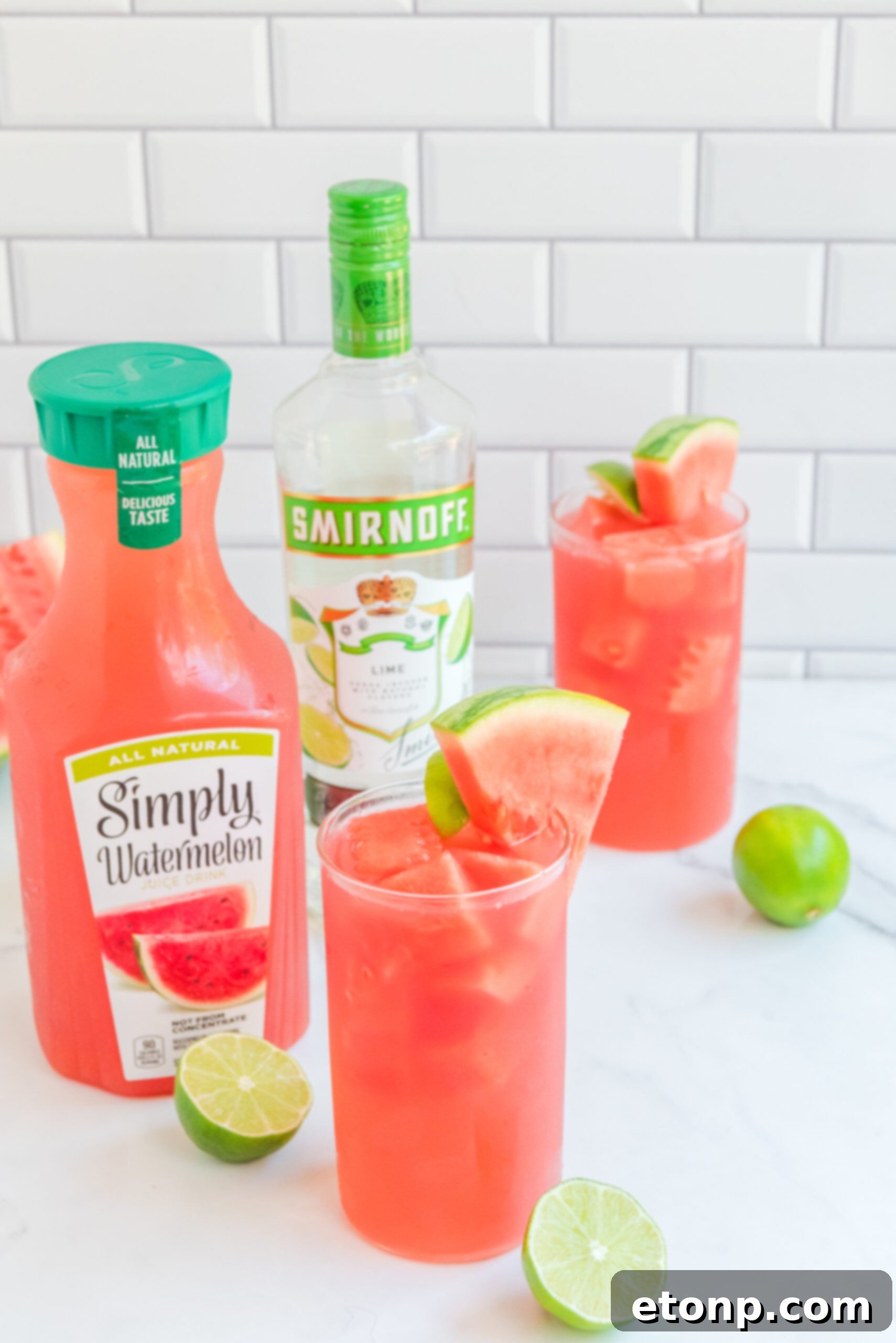 Front view of Watermelon Cocktail in two clear glasses garnished with lime and watermelon slices.