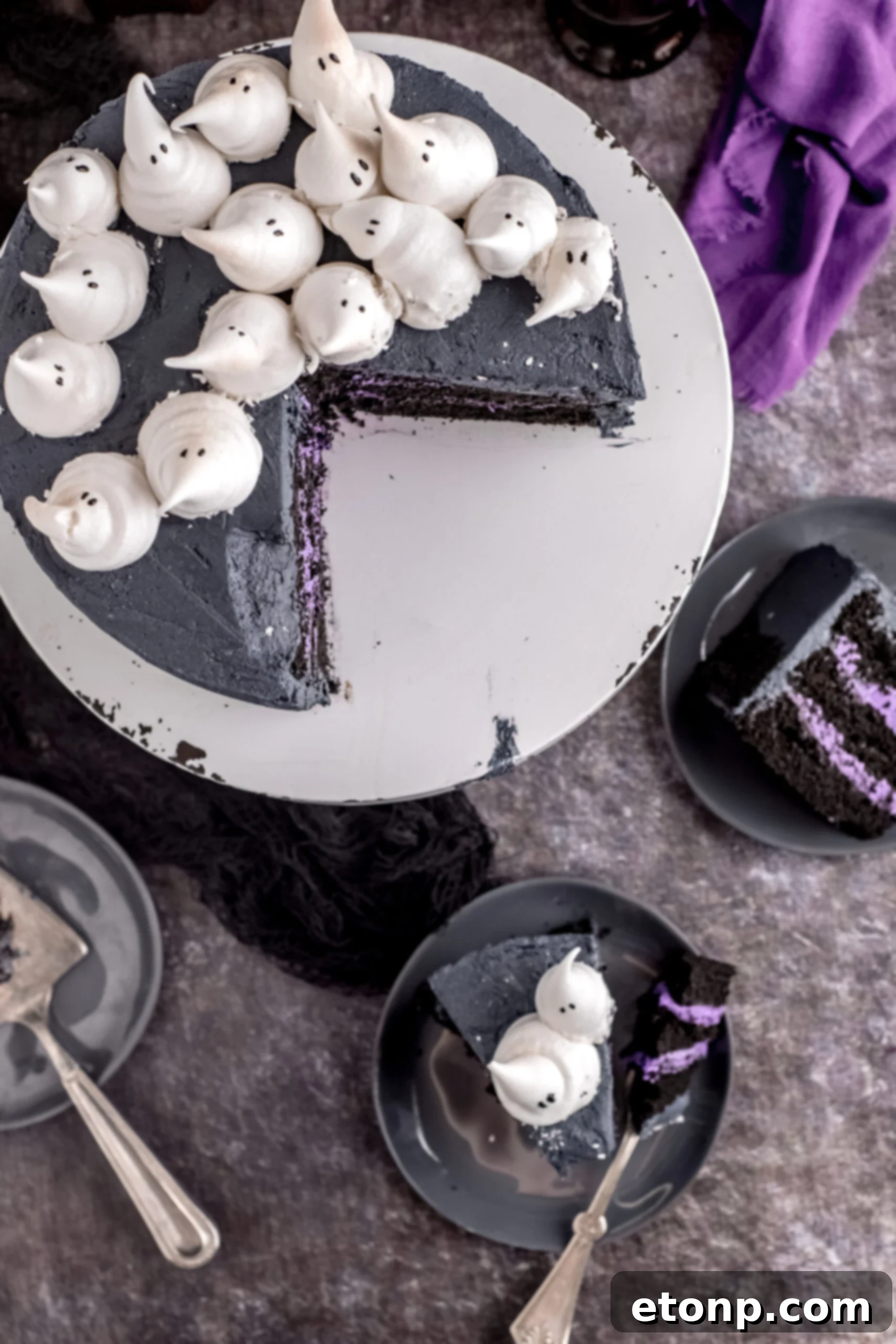 Overhead view of the Halloween cake with two pieces being served on gray plates. 