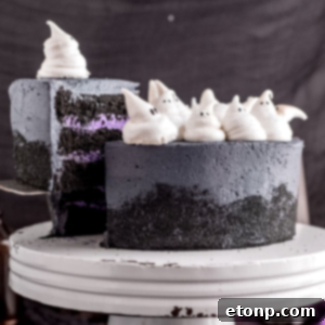 A beautifully decorated Halloween Cake with purple and black frosting, topped with meringue ghosts.