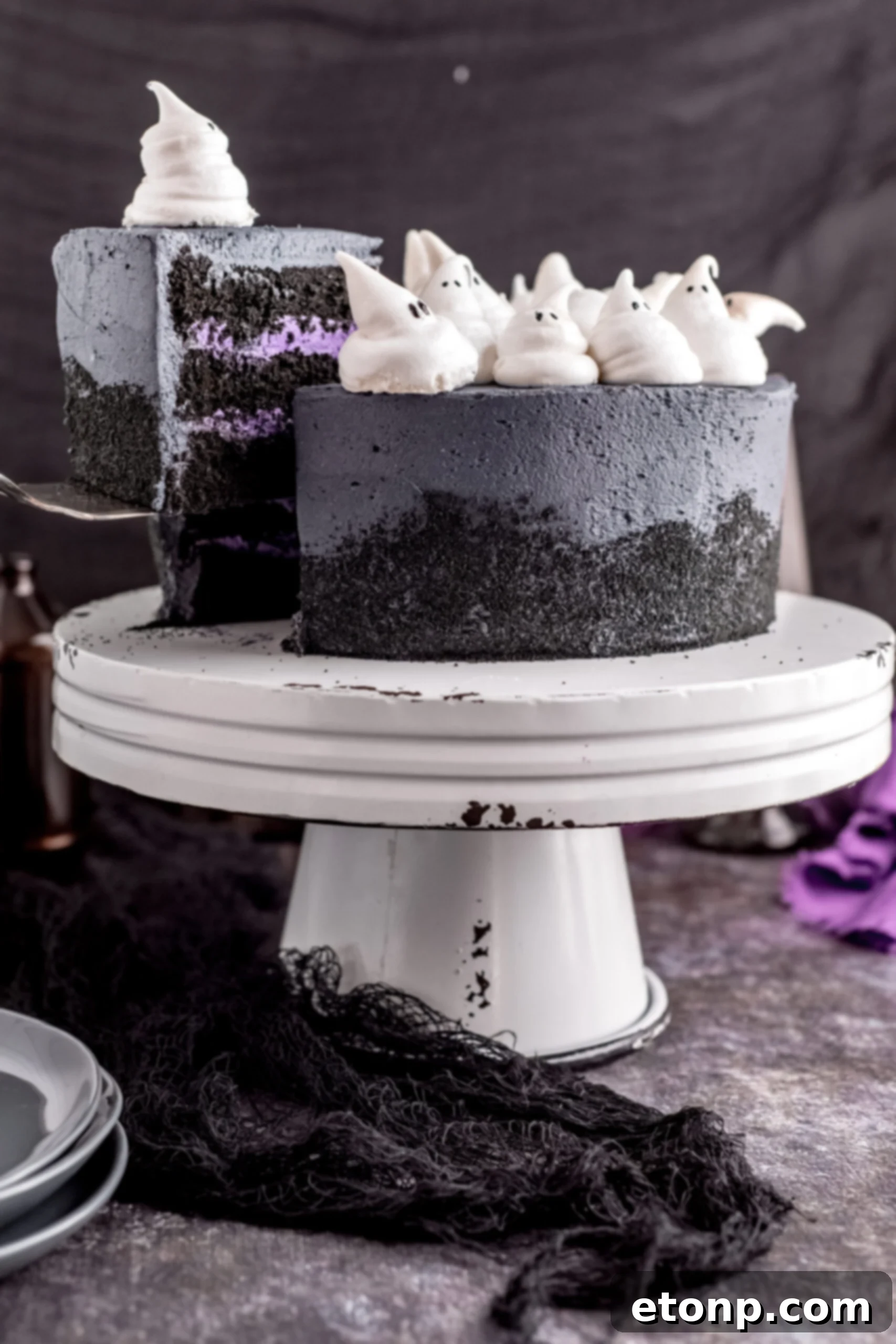Halloween Cake on a white distressed stand with a piece being removed with a silver spatula. 