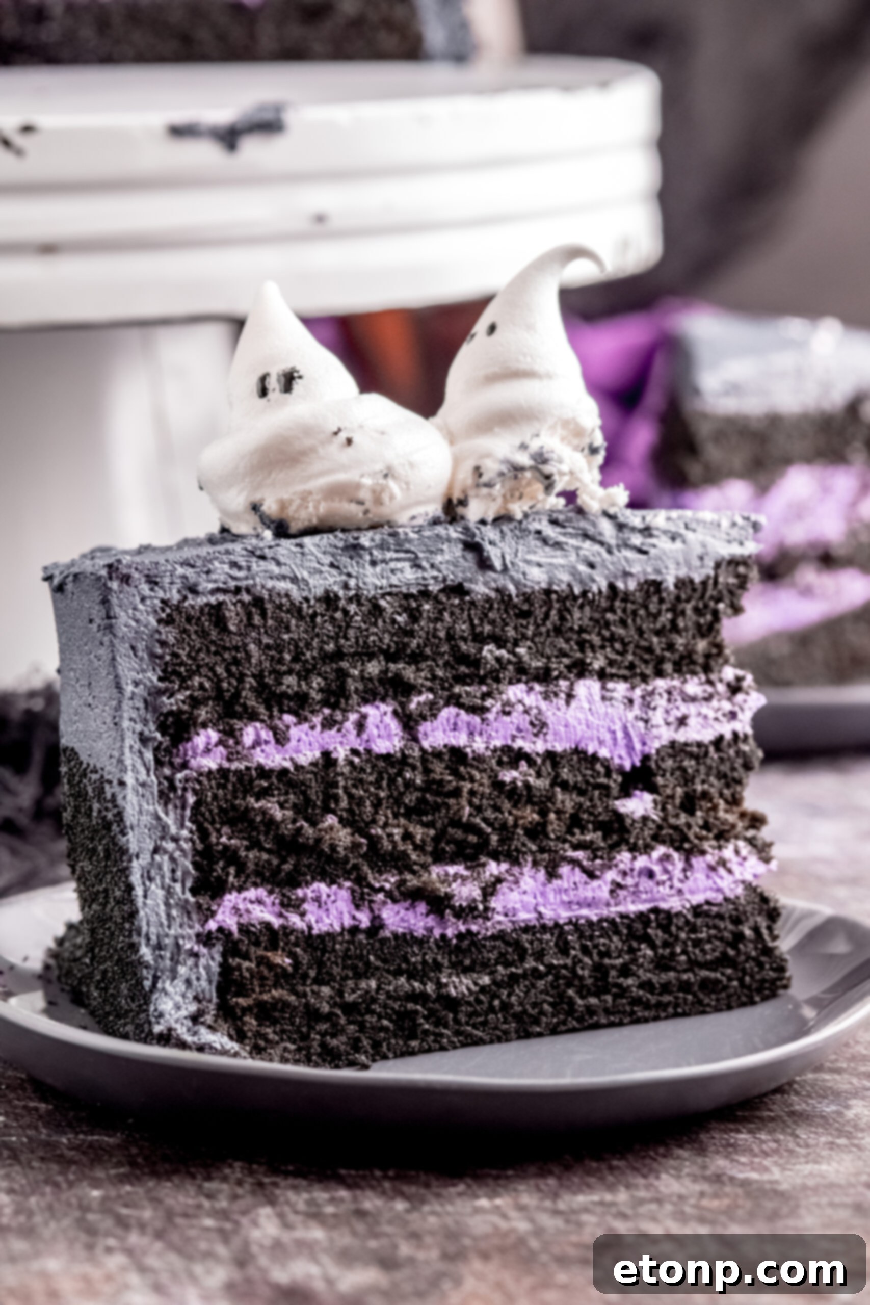 Side view of the Halloween cake slice on black plate showing the purple frosting layers