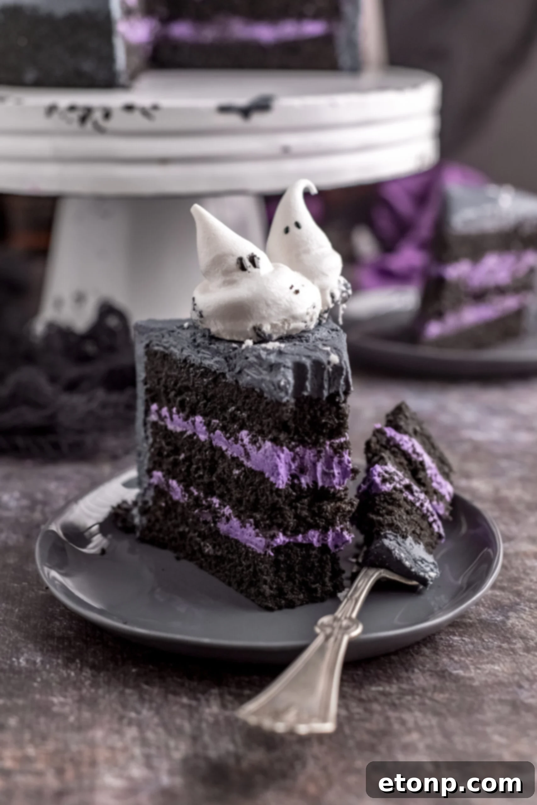 A piece of Halloween Cake on a gray plate with a bite removed. 