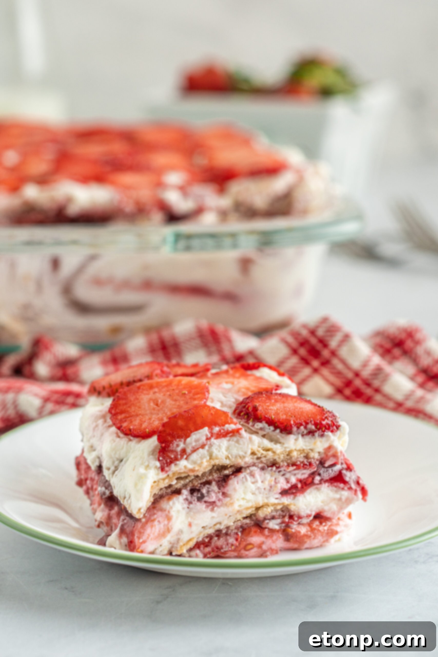 A beautifully presented piece of Strawberry Cheesecake Icebox Cake resting on an elegant white and green plate, highlighting its neat layers.