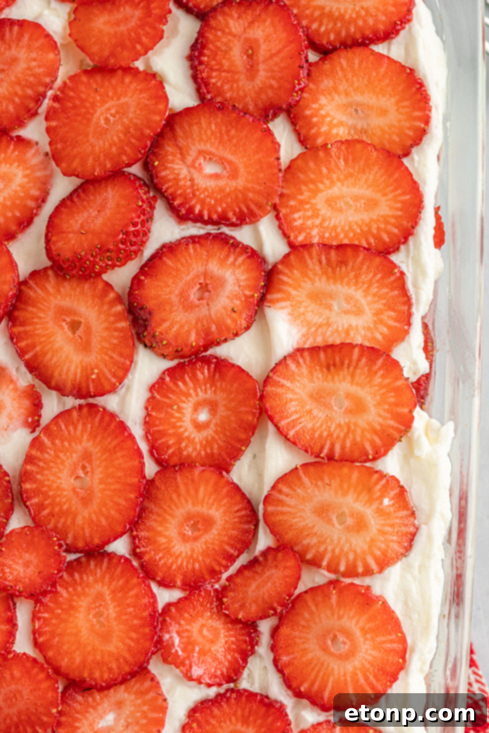 A captivating up-close shot of the glistening fresh strawberry topping, highlighting its vibrant color and juicy texture.