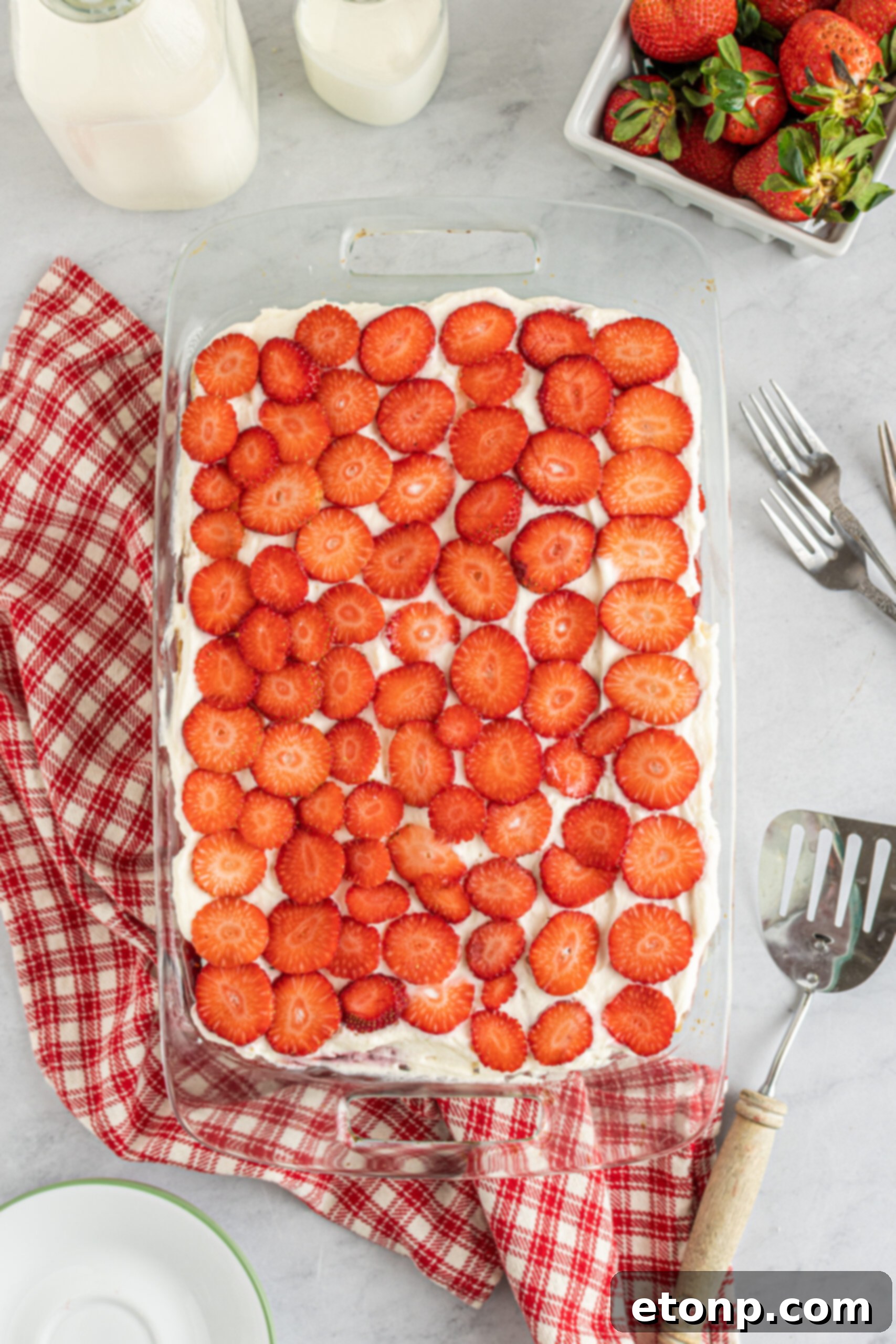 An inviting overhead view of a freshly prepared Strawberry Cheesecake Icebox Cake nestled in a clear glass baking dish, ready for chilling.
