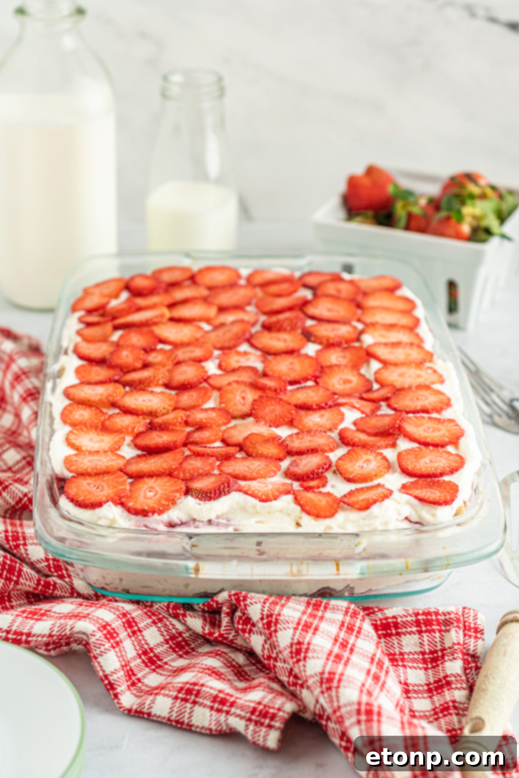 A perfect side view of the Strawberry Cheesecake Icebox Cake, showcased in a clear baking dish, highlighting its meticulously arranged layers.