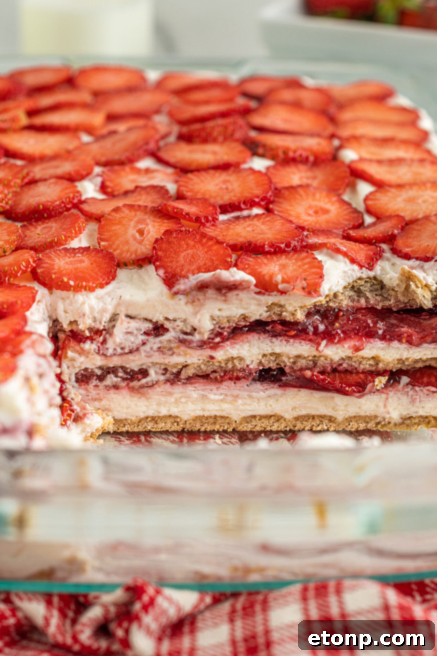 An intricate close-up shot showcasing the distinct layers of the Strawberry Cheesecake Icebox Cake, highlighting the creamy filling, strawberry preserves, and softened graham crackers.