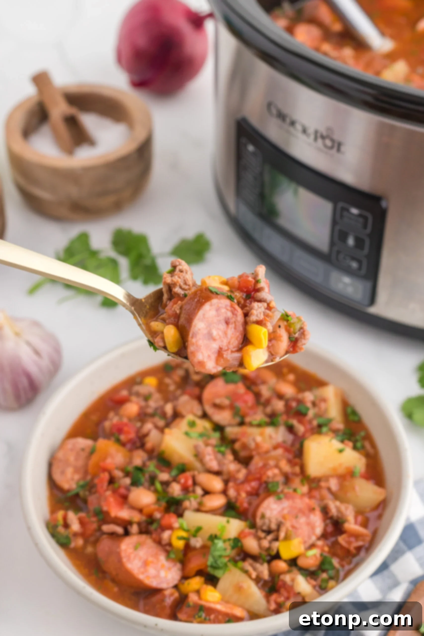 Hearty Lone Star Slow Cooker Stew 16 Close up view of a perfect bite of Slow Cooker Texas Cowboy Stew on a silver spoon, showing chunks of beef, sausage, and vegetables.