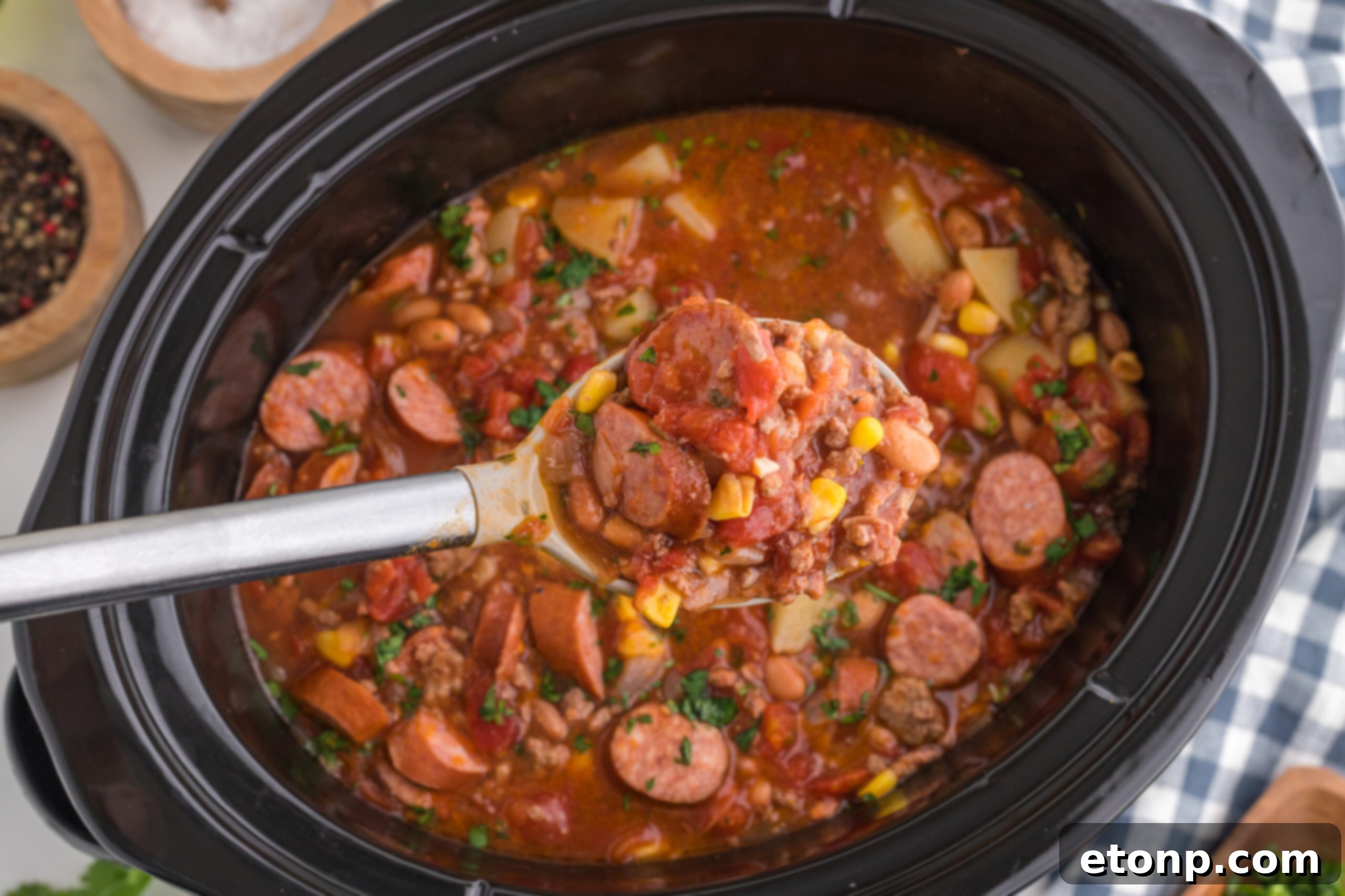 Hearty Lone Star Slow Cooker Stew 4 Overhead view of Slow Cooker Texas Cowboy Stew in a crockpot with a spoon removing a generous serving.
