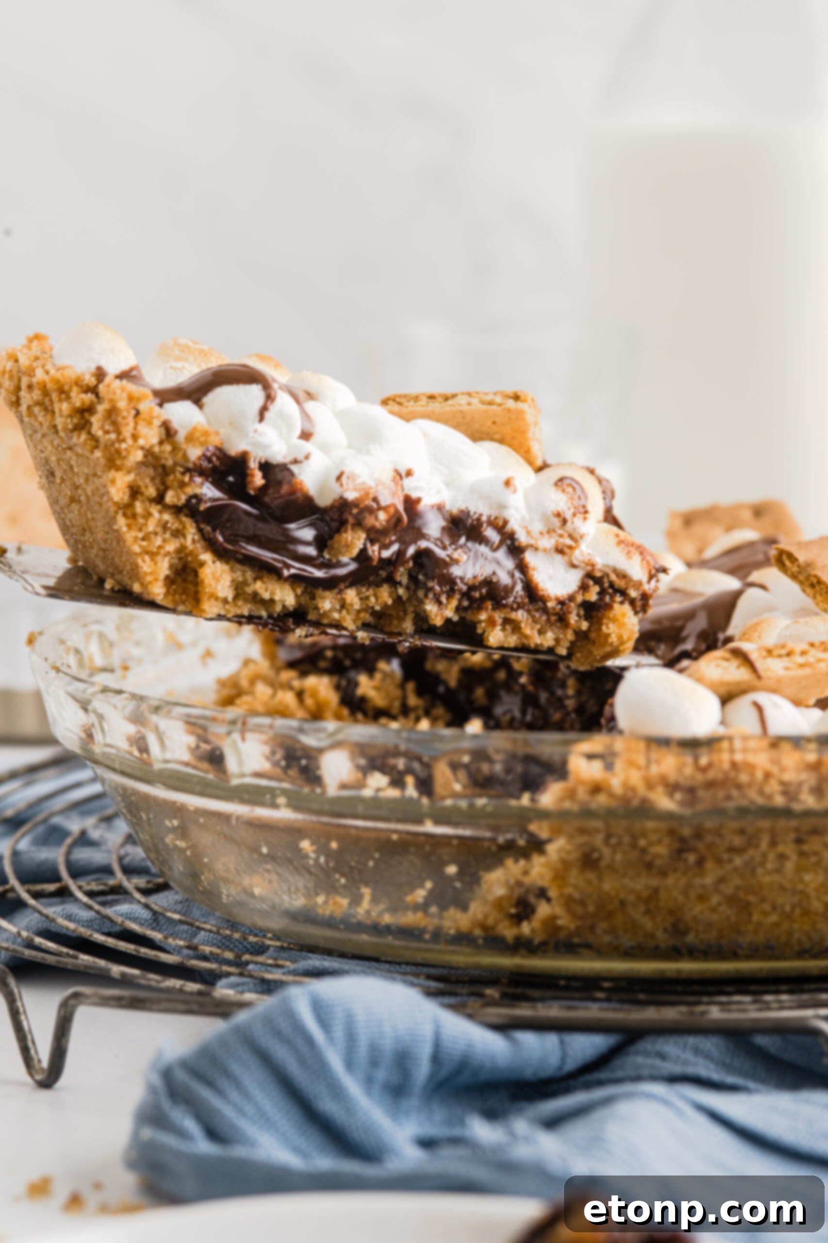 A piece of S'mores Pie being removed from the baking dish with a silver spatula. 