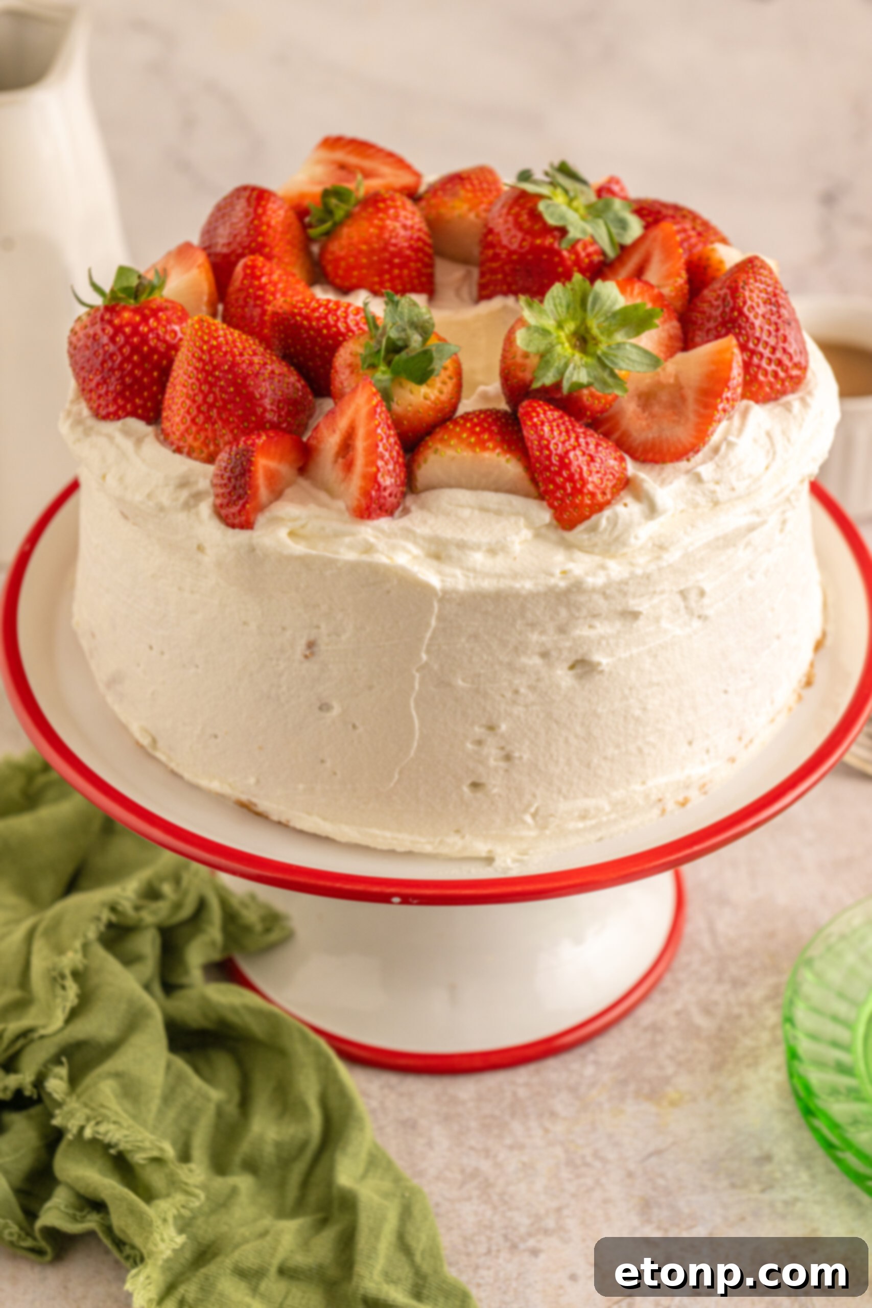 Side view of the freshly baked Strawberry Angel Food Cake, beautifully topped with an abundance of fresh strawberries.