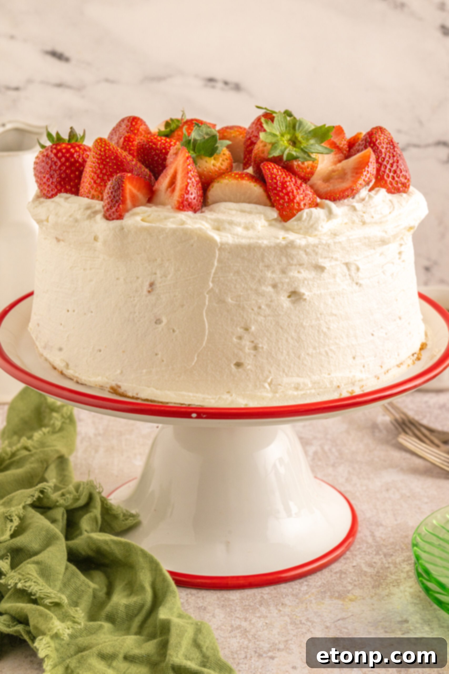 The complete Strawberry Angel Food Cake, generously topped with fresh strawberries and artistically presented on an elegant cake stand.