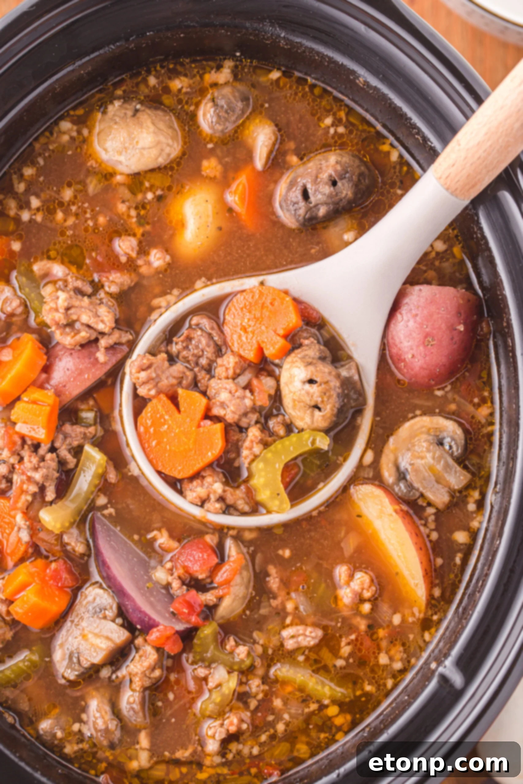 Overhead view of a serving spoon removing a serving of Witches Brew Stew.
