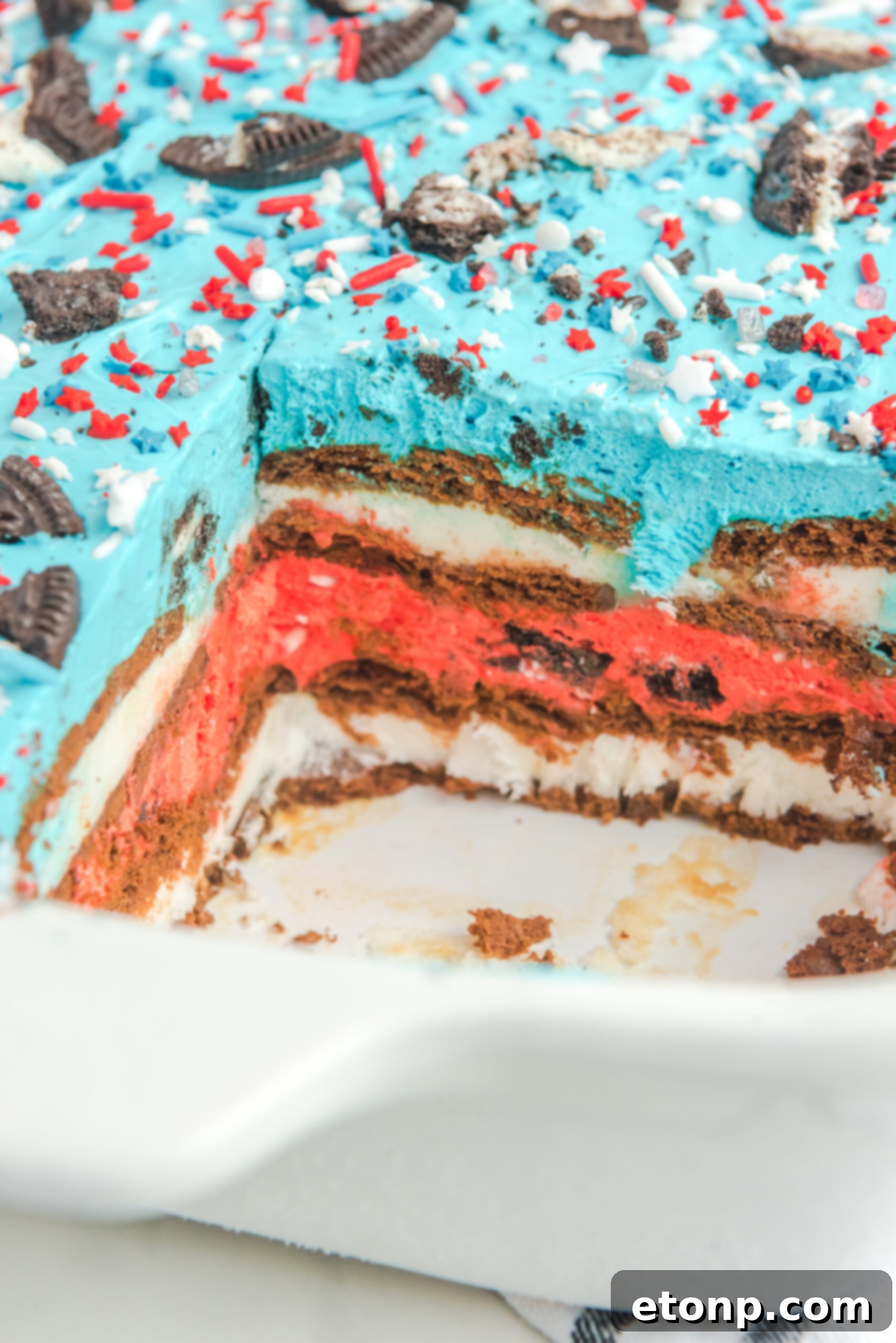 Close up view of Patriotic Ice Cream Sandwich Cake in a baking dish with a slice removed.
