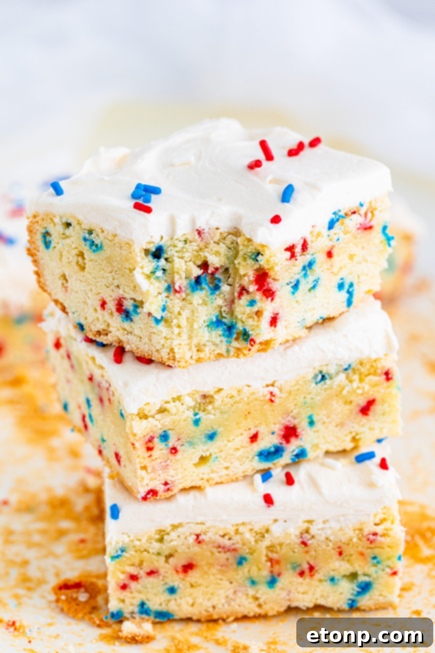 Front view of three Patriotic Sugar Cookie Bars stacked with a bite removed from the top bar.