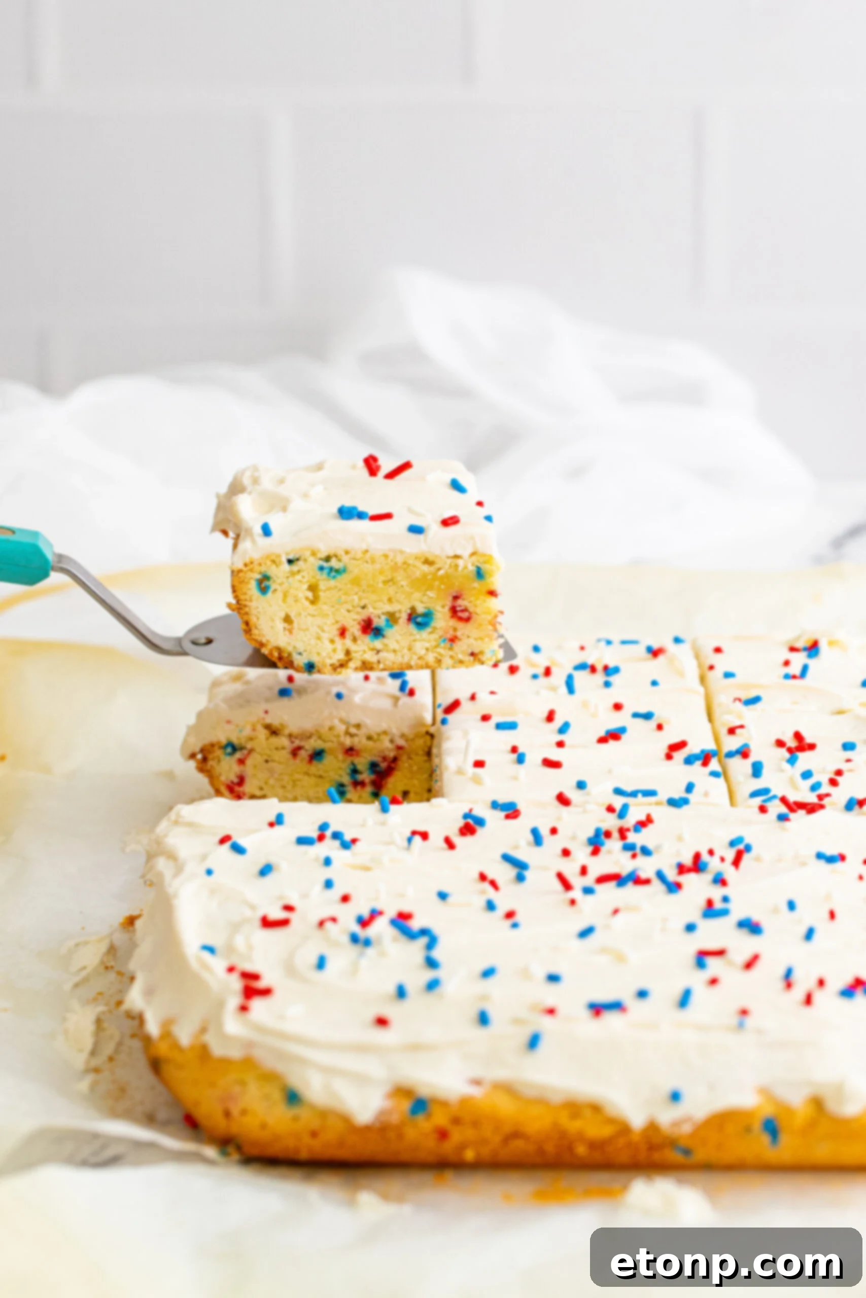 Front view of a cake server removing a piece of Patriotic Sugar Cookie Bars.