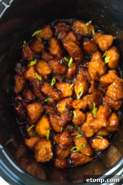 The prepared firecracker sauce being poured over the browned chicken in the slow cooker.