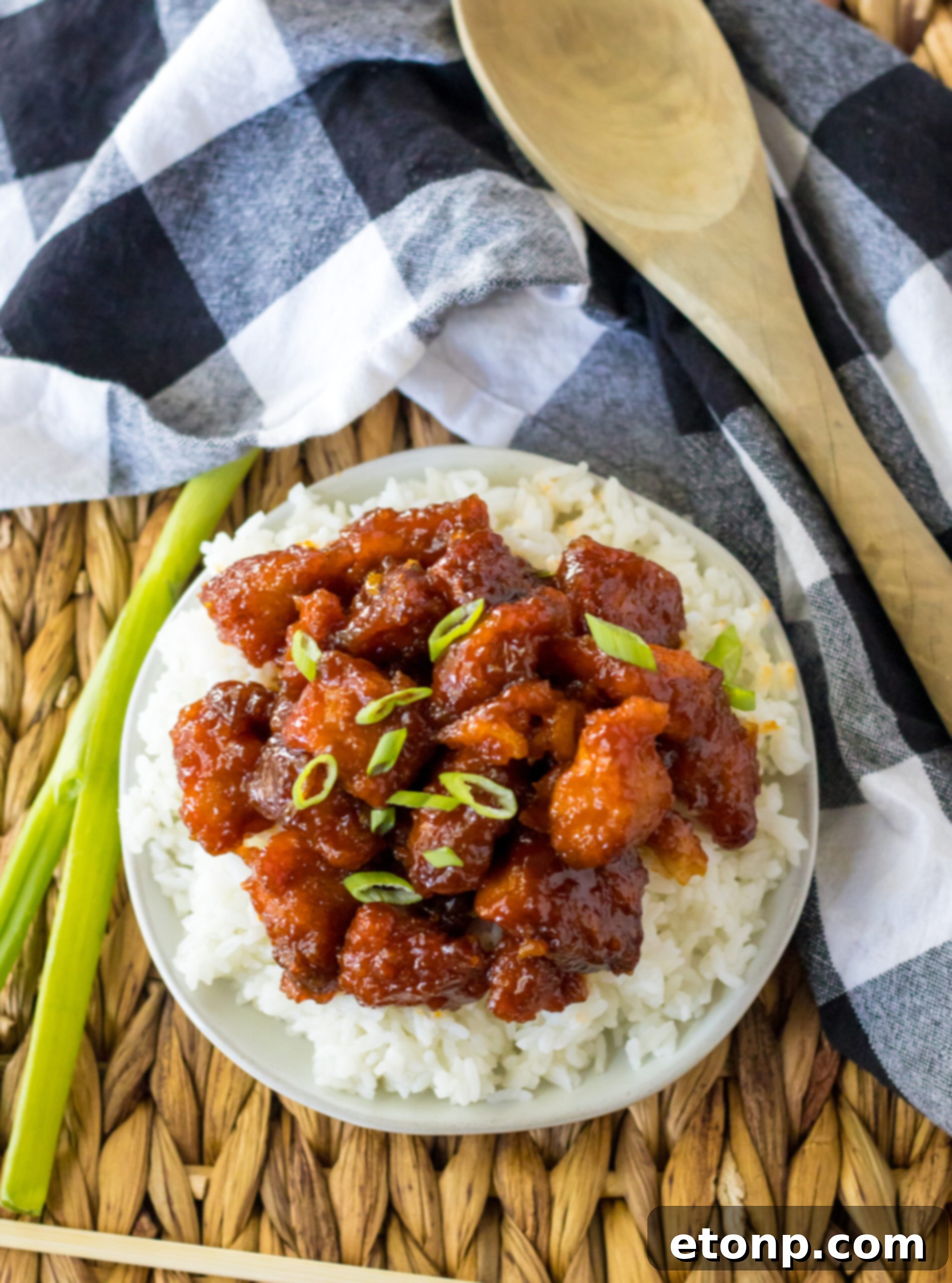 Overhead view of Slow Cooker Firecracker Chicken served over white rice in a white bowl, garnished with fresh scallions.