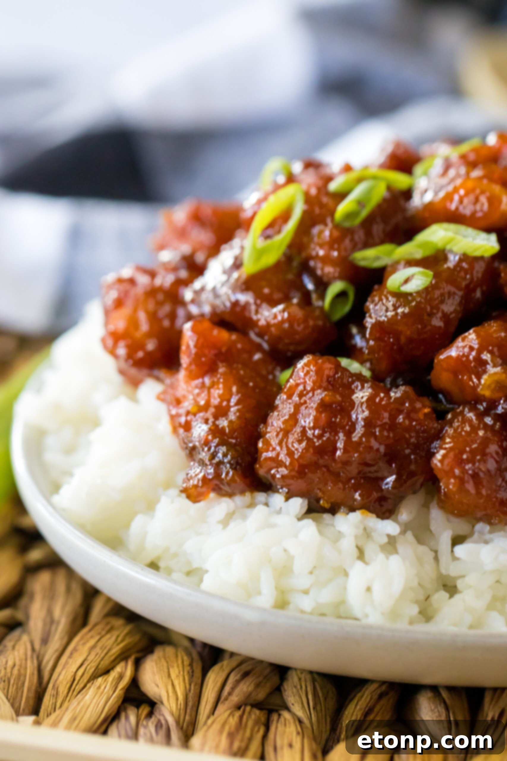 Close-up overhead shot of Slow Cooker Firecracker Chicken with steam rising, served over white rice in a bowl.
