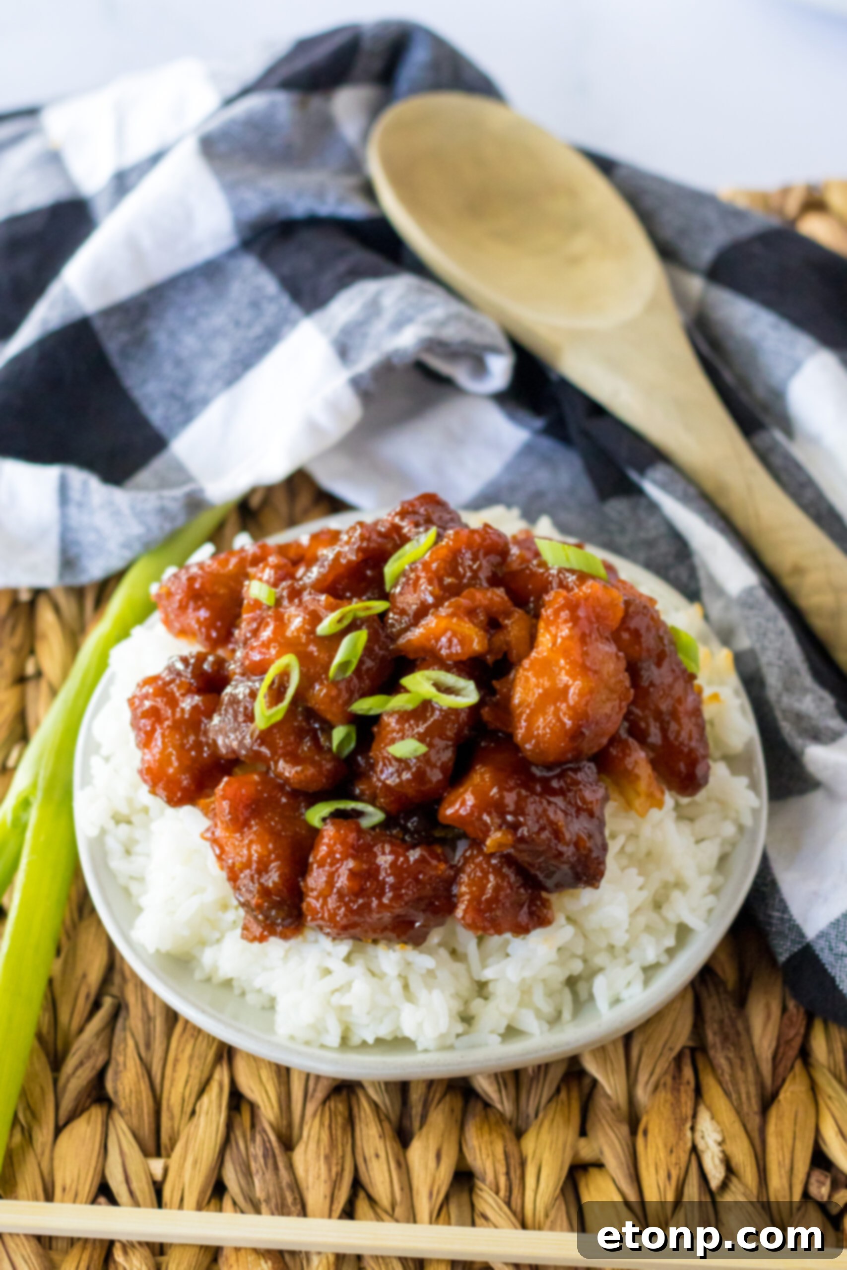 Overhead view of a perfectly plated portion of Slow Cooker Firecracker Chicken over white rice in a white bowl.