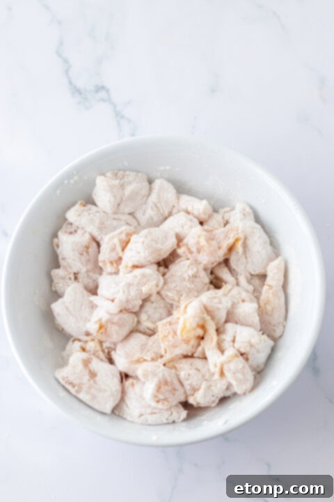 Diced chicken pieces browning in a hot skillet with oil.