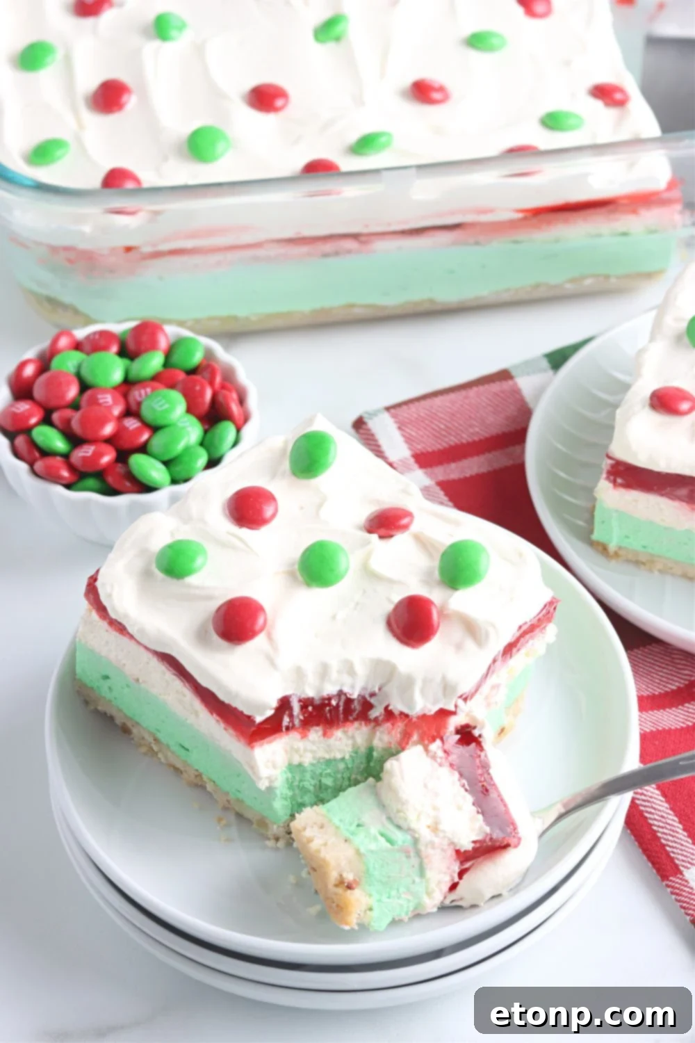 A close-up of a bite of Christmas dessert lasagna on a fork, held above a plate, highlighting the distinct layers and inviting texture.
