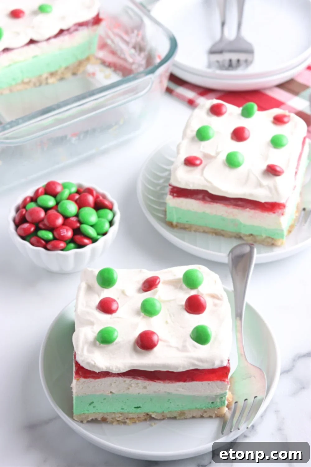 Multiple plates on a table, each holding a vibrant slice of the layered Christmas Jello dessert, ready for guests to enjoy during the holiday season.