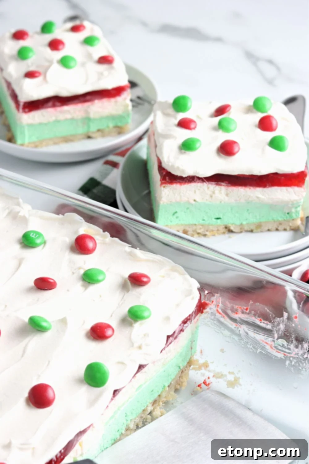 A full 9x13 inch baking pan showcases the beautiful, distinct layers of the Christmas dessert lasagna, perfectly set and ready for slicing.