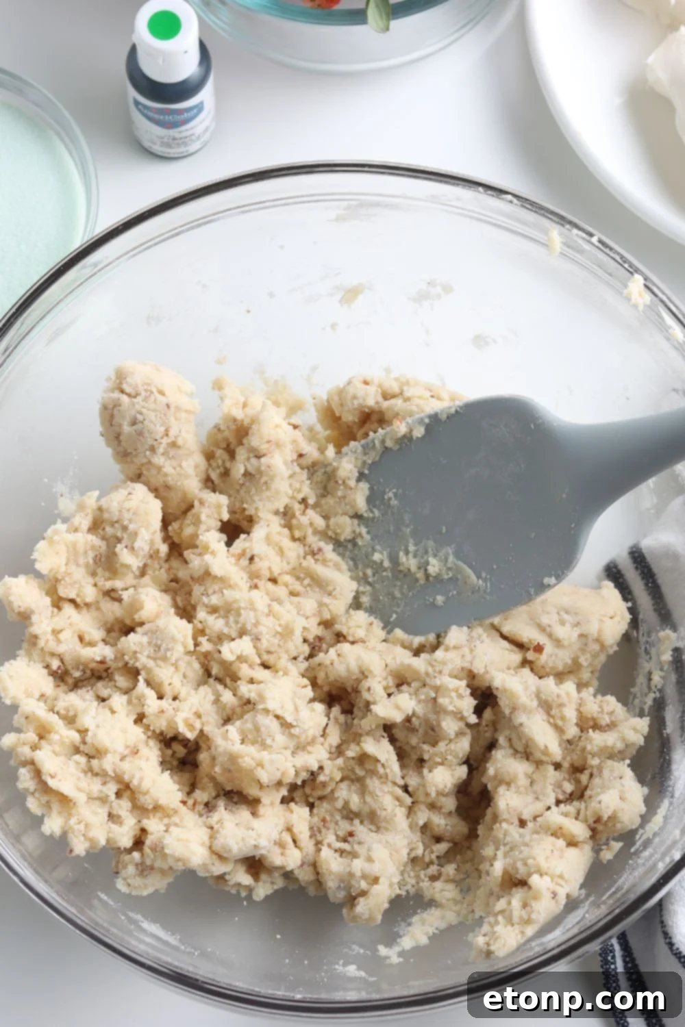 A bowl of mixed crust ingredients for the Christmas lasagna dessert, showing a crumbly texture before pressing into the pan.