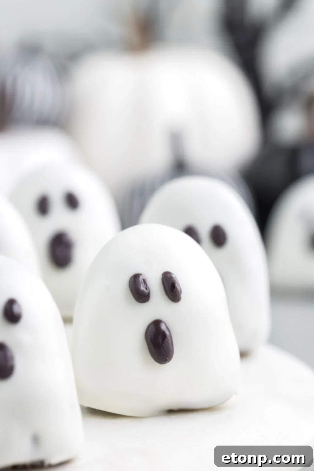 A spread of adorable spooky ghost Oreo truffles neatly arranged on a table, showcasing their charming decorations.
