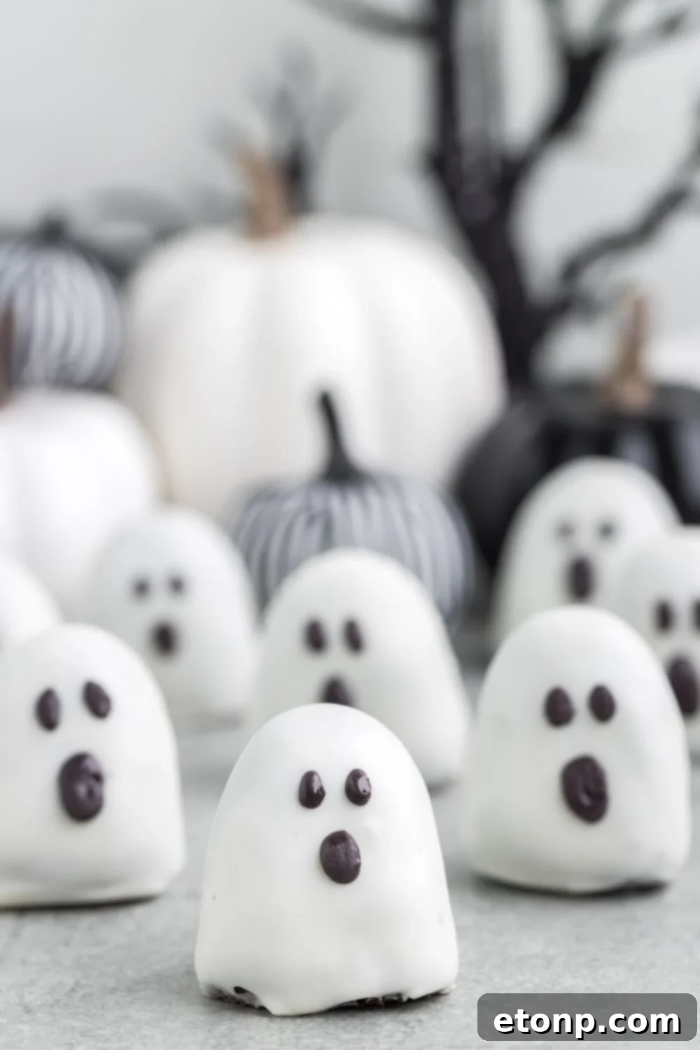 A delightful array of spooky Oreo truffles presented on a table, with decorative fabric pumpkins providing a festive Halloween backdrop.