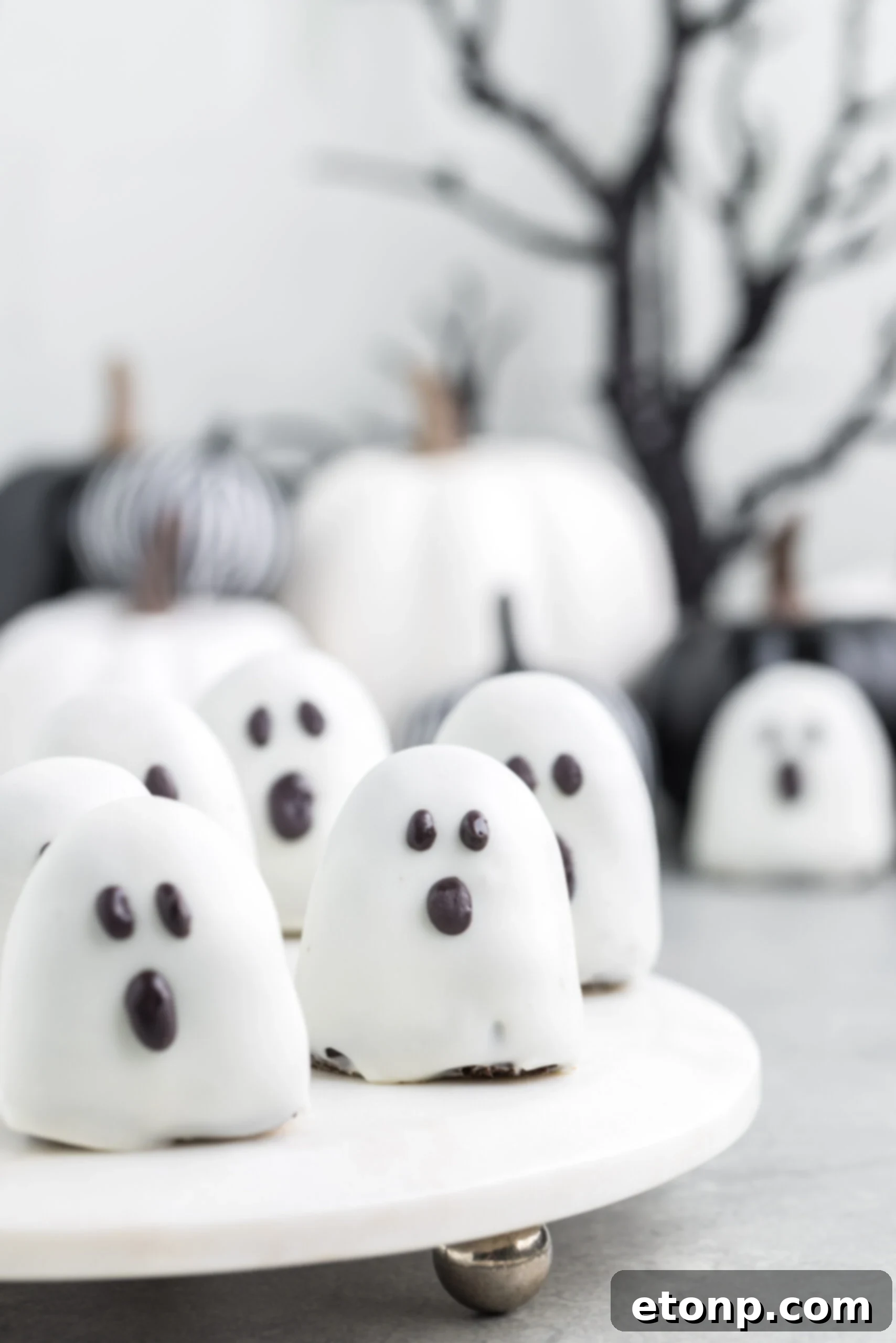 A festive display of spooky Oreo truffles arranged on a pristine white marble serving tray, ready for a Halloween celebration.