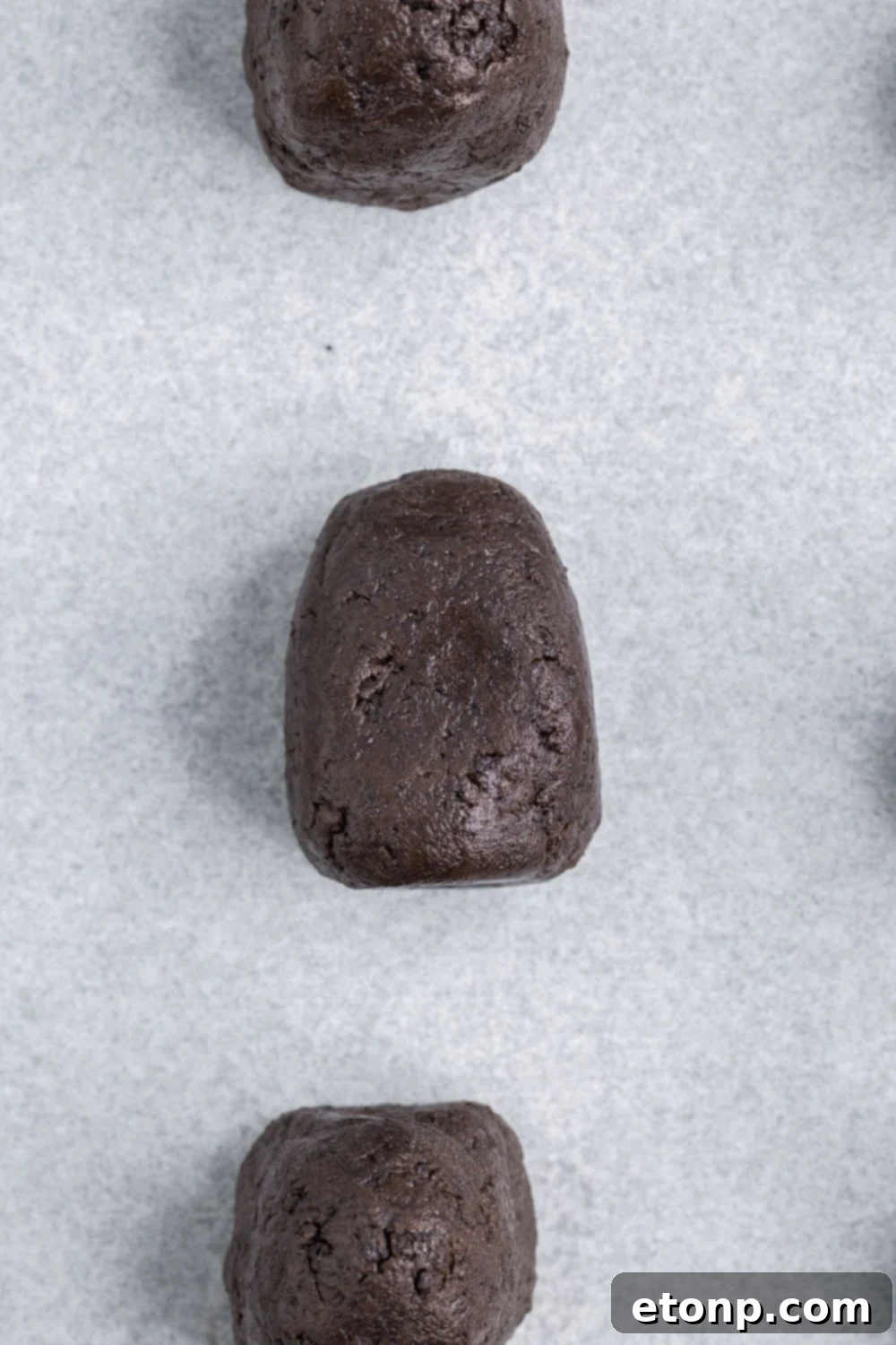 A batch of Oreo truffle mixture expertly shaped into a distinct bell form, destined to become a ghostly figure.
