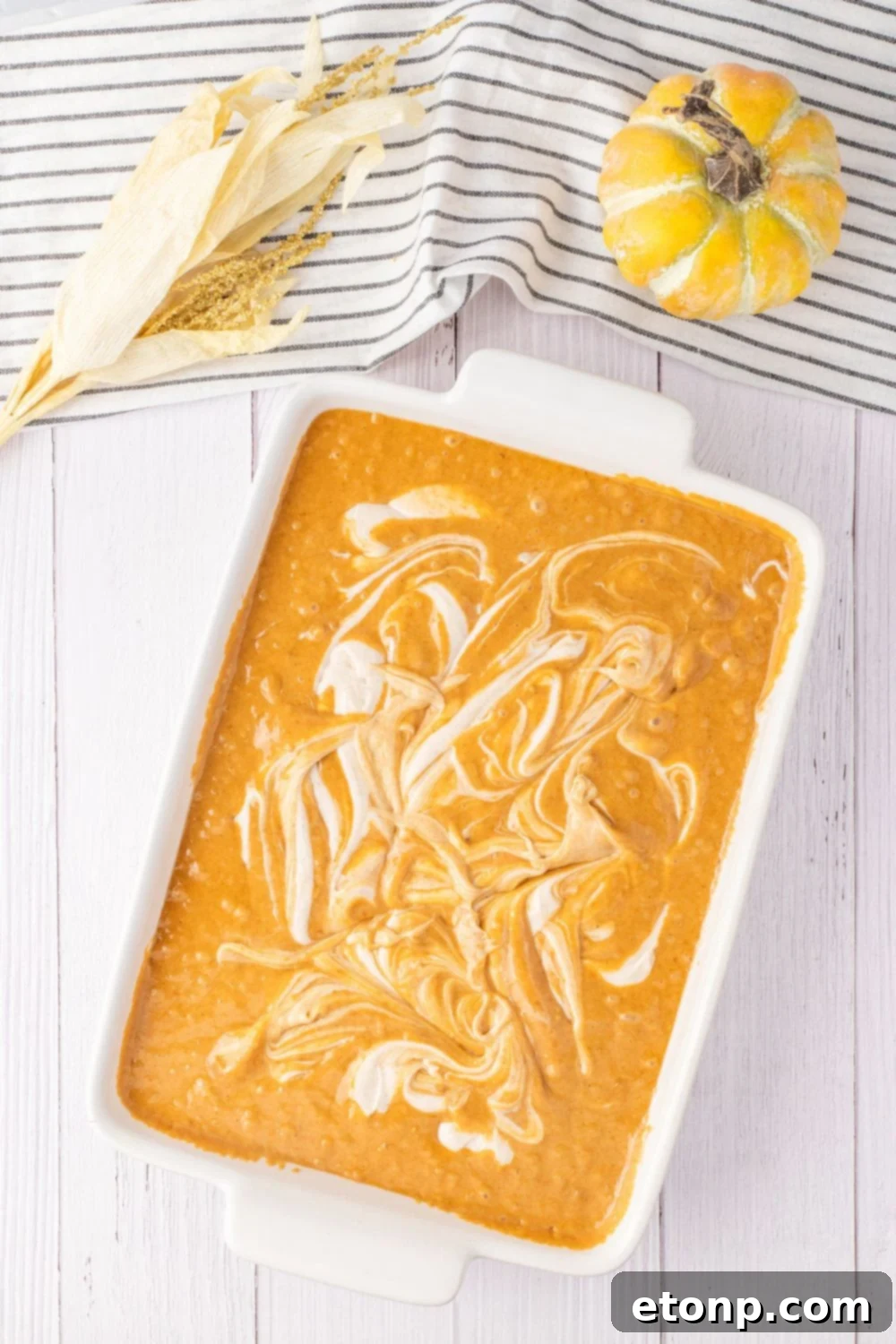 cream cheese batter swirled in pan of pumpkin cake batter