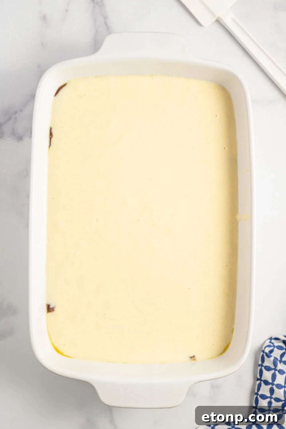 Dolce Vita Cake 10 ricotta batter being poured into a 9x13 baking dish over chocolate cake batter