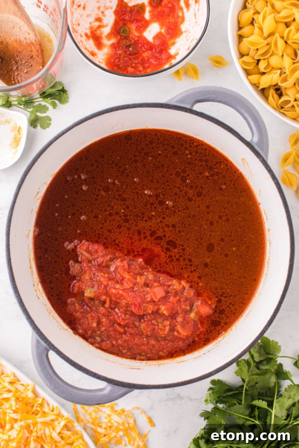 Cheesy Taco Pasta 11 Salsa and beef broth simmering in a pot on the stovetop, forming the base of the taco pasta sauce.