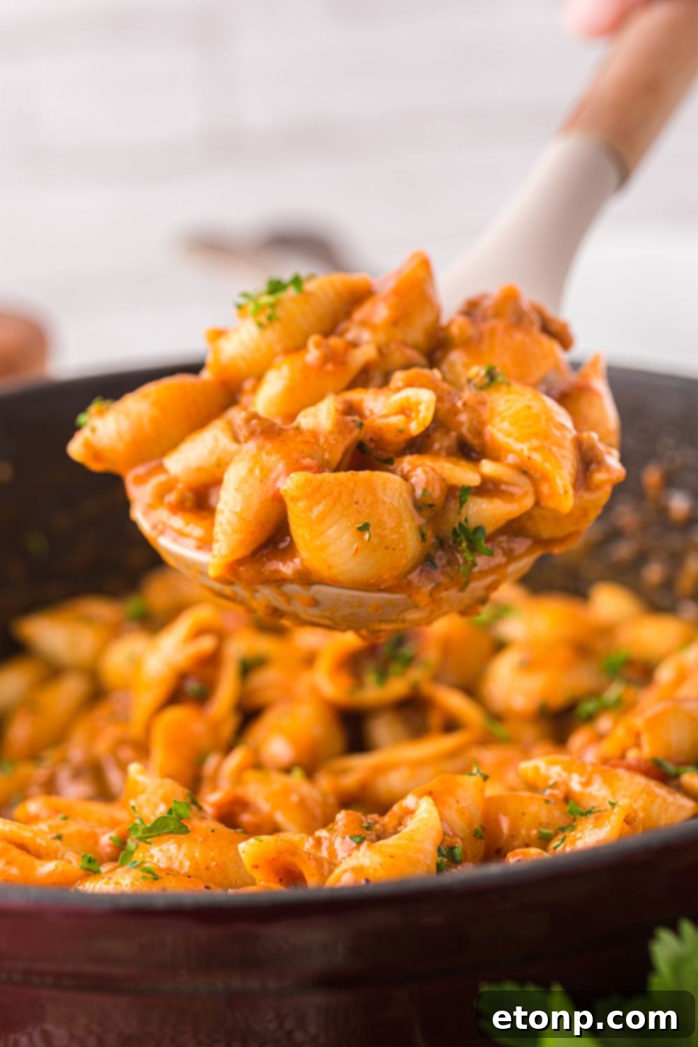 Cheesy Taco Pasta 15 A serving spoon lifting a portion of cheesy taco pasta from the pan, showing its creamy consistency.