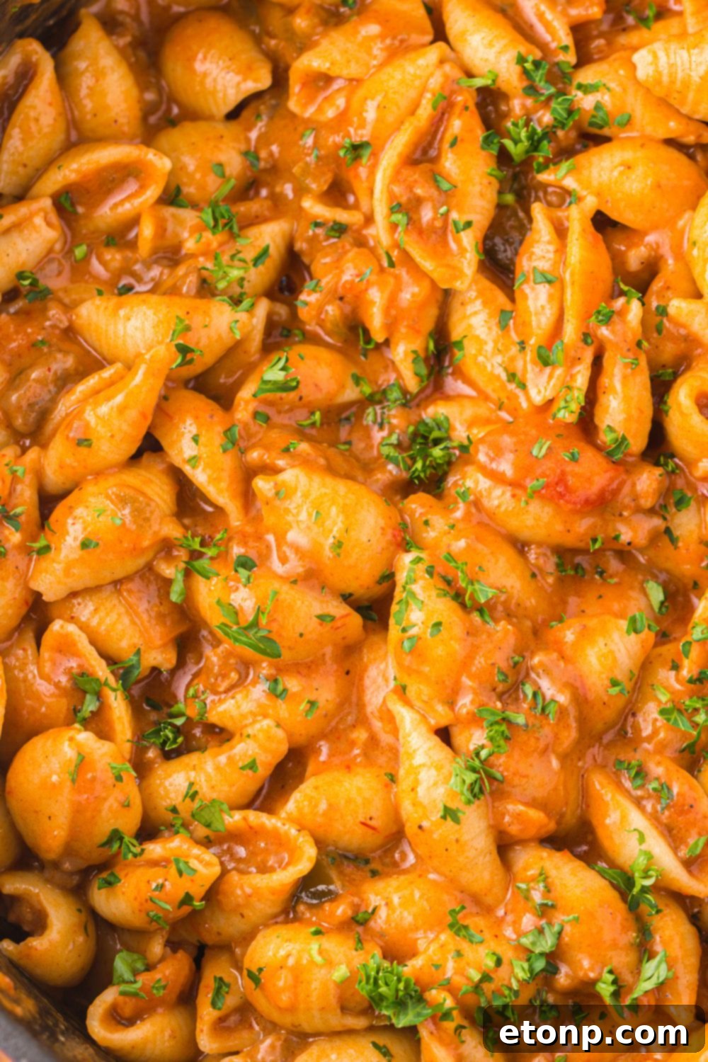 Cheesy Taco Pasta 16 An overhead shot of cheesy taco pasta simmering in a skillet on the stove, steam gently rising.
