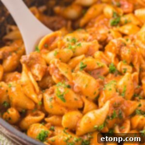 Delicious taco pasta in a pan, ready to be served with a wooden spoon.